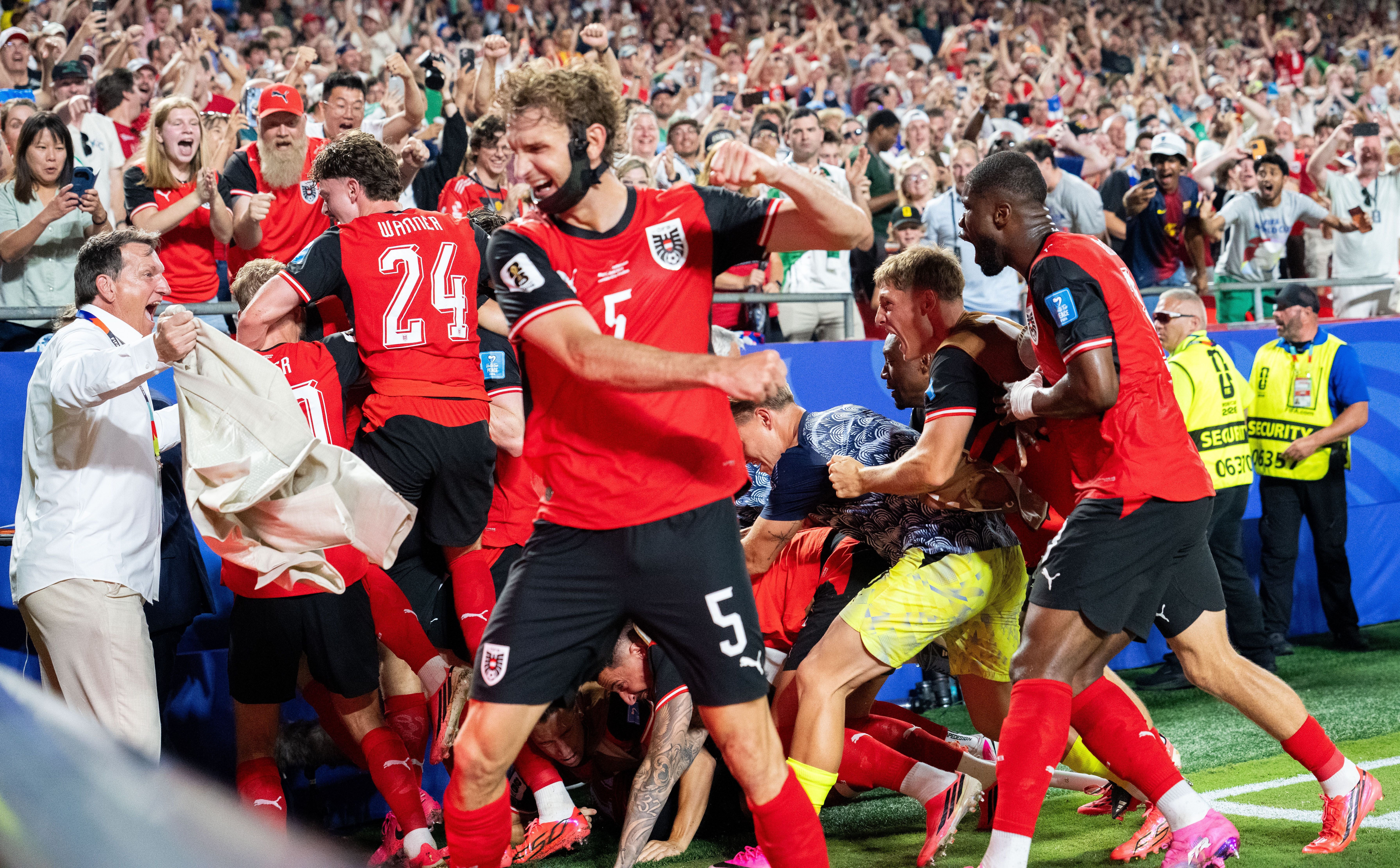 Österreichische Fußballspieler jubeln nach einem Tor, umgeben von jubelnden Fans im Stadion.