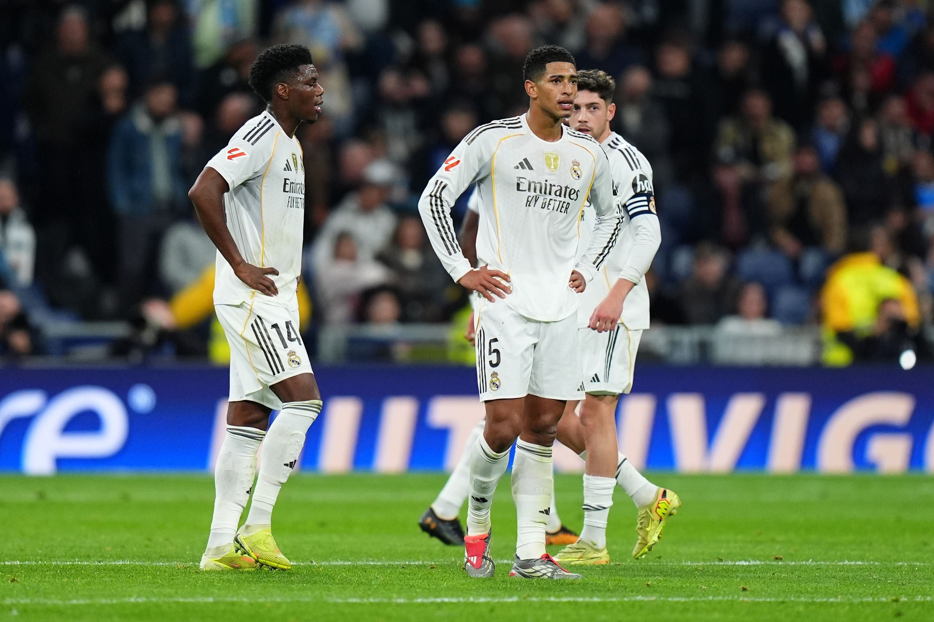 Drei Real-Madrid-Spieler stehen enttäuscht auf dem Spielfeld während eines Fußballspiels.