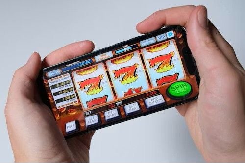 Person hält ein Smartphone mit einem virtuellen Spielautomaten-Spiel auf dem Bildschirm.