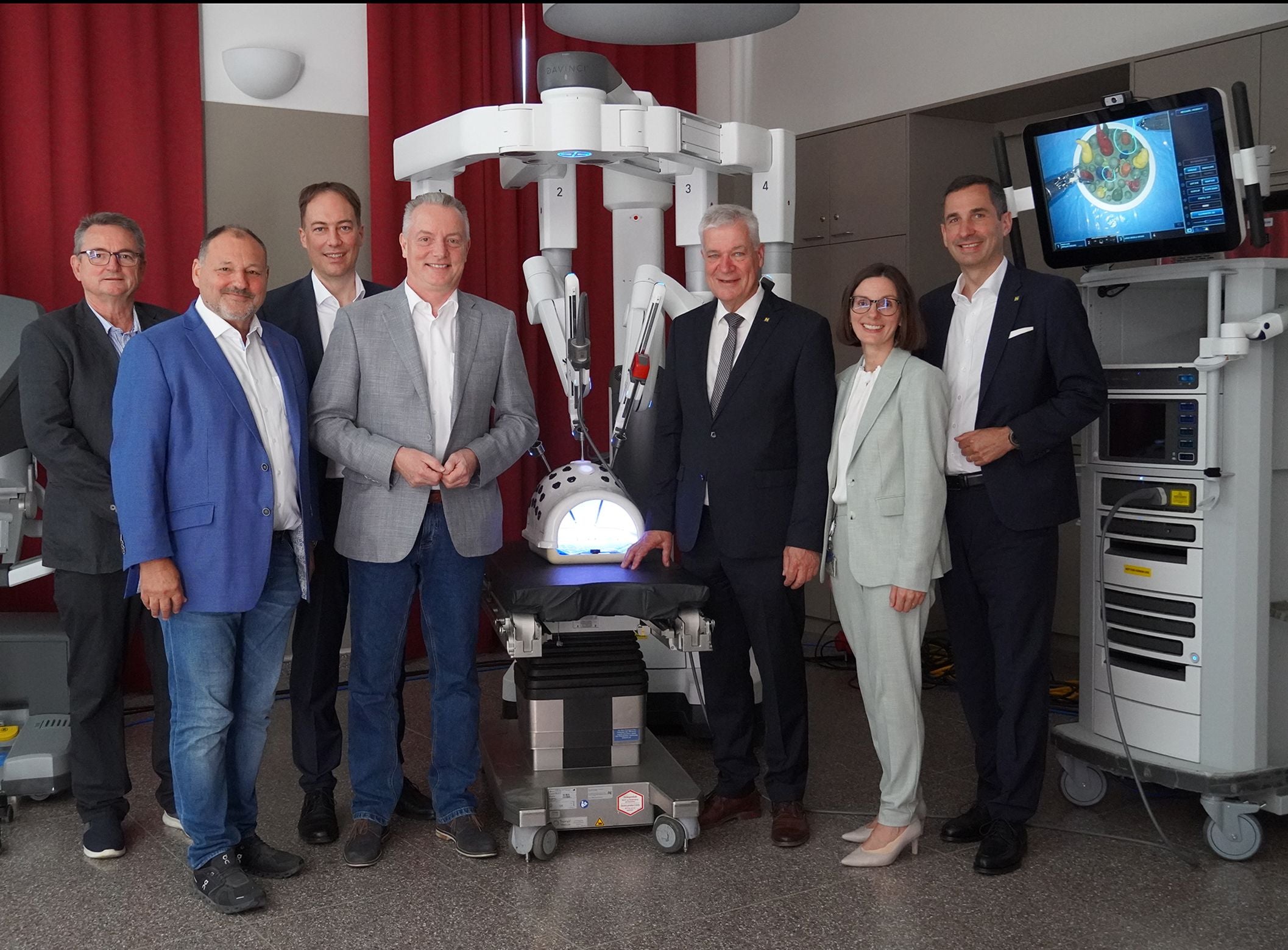 Eine Gruppe von sieben Personen steht vor einem medizinischen Operationsroboter.