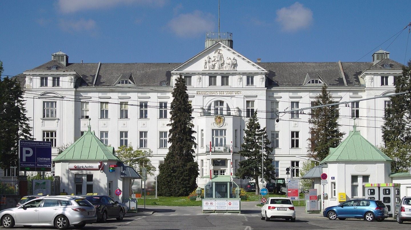 Haupteingang der Klinik Hietzing in Wien mit davor parkenden Autos.