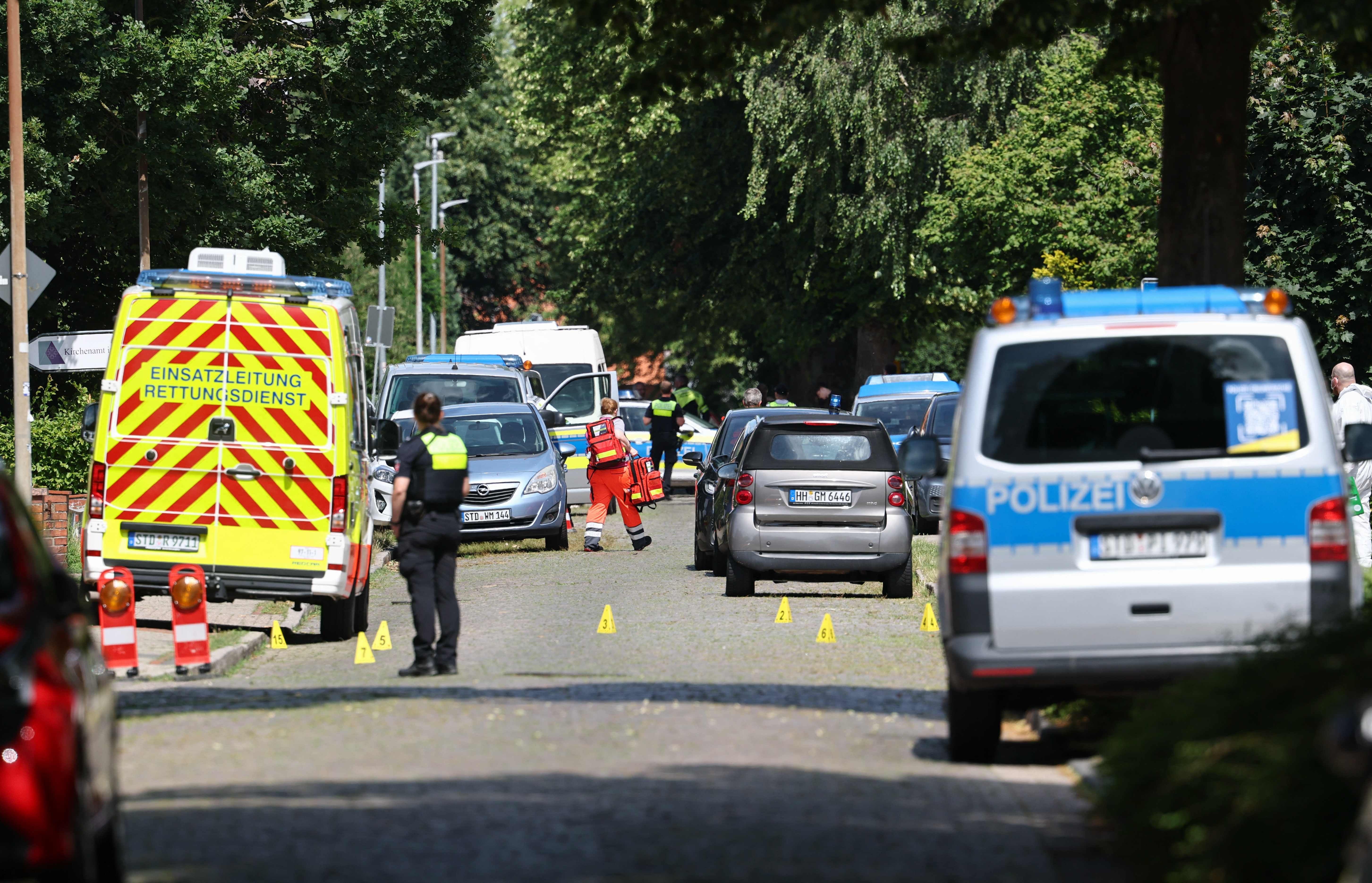 Polizei- und Rettungsfahrzeuge stehen an einem Tatort in einer Wohnstraße, Markierungen auf der Straße.