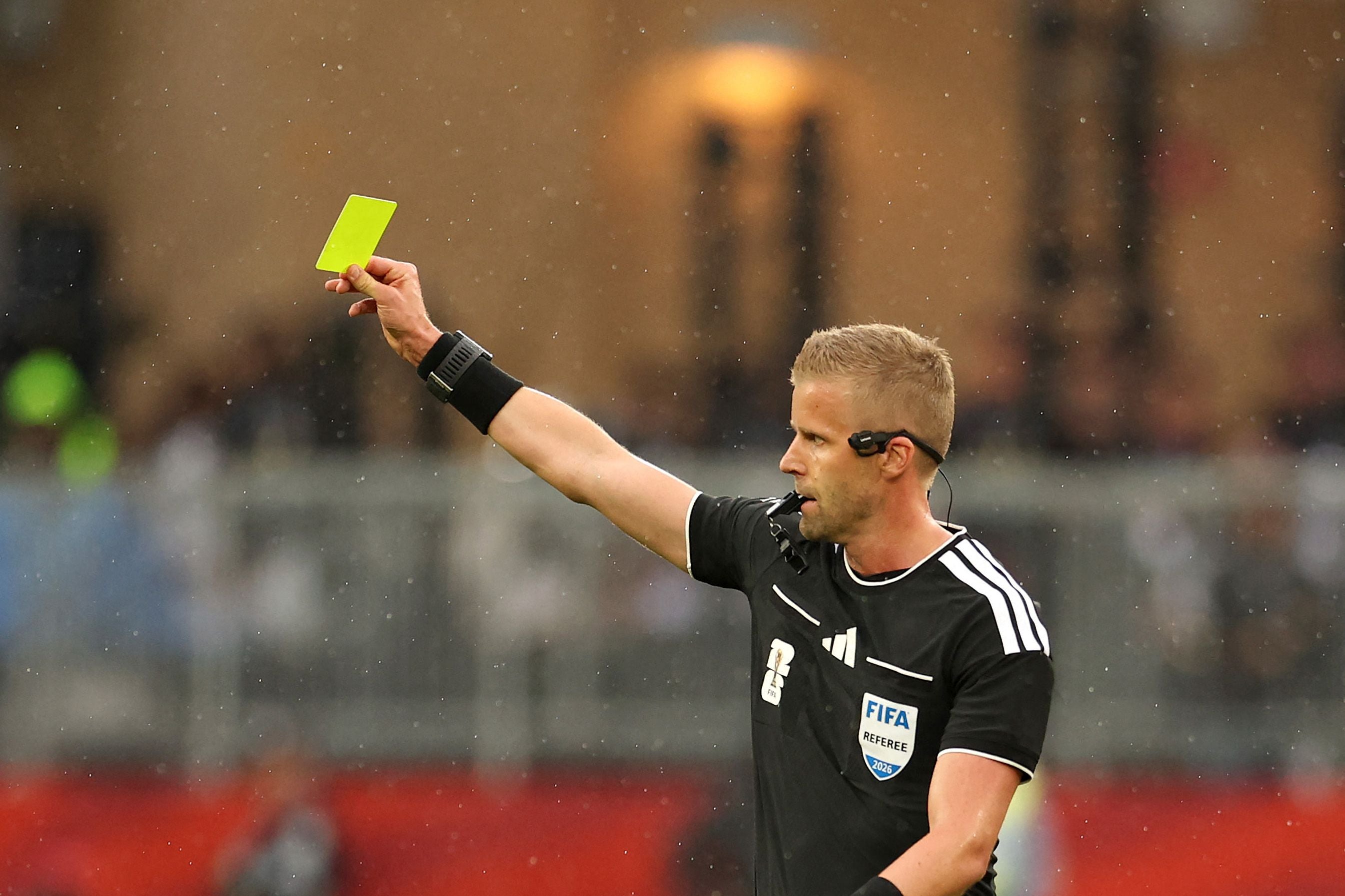 Ein Schiedsrichter zeigt während eines Fußballspiels eine gelbe Karte.