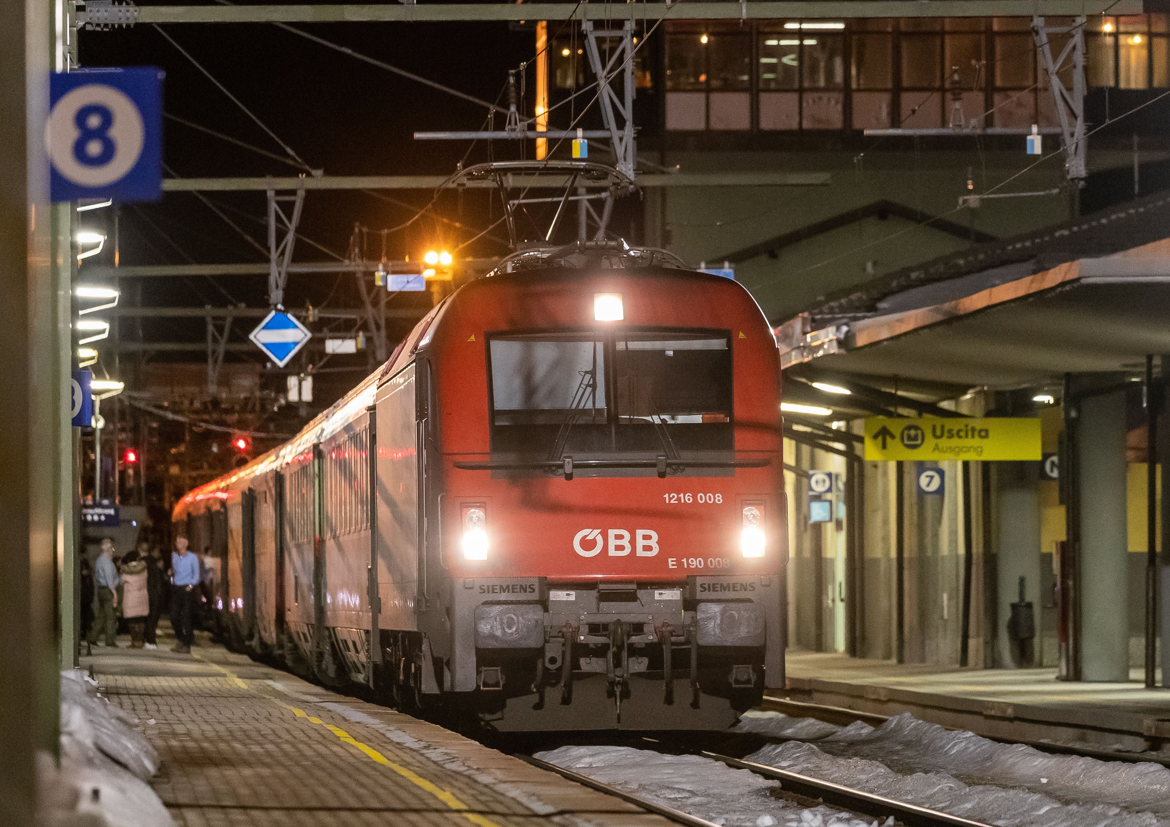Ein roter ÖBB-Personenzug steht nachts am beleuchteten Bahnsteig des Bahnhofs Brenner.