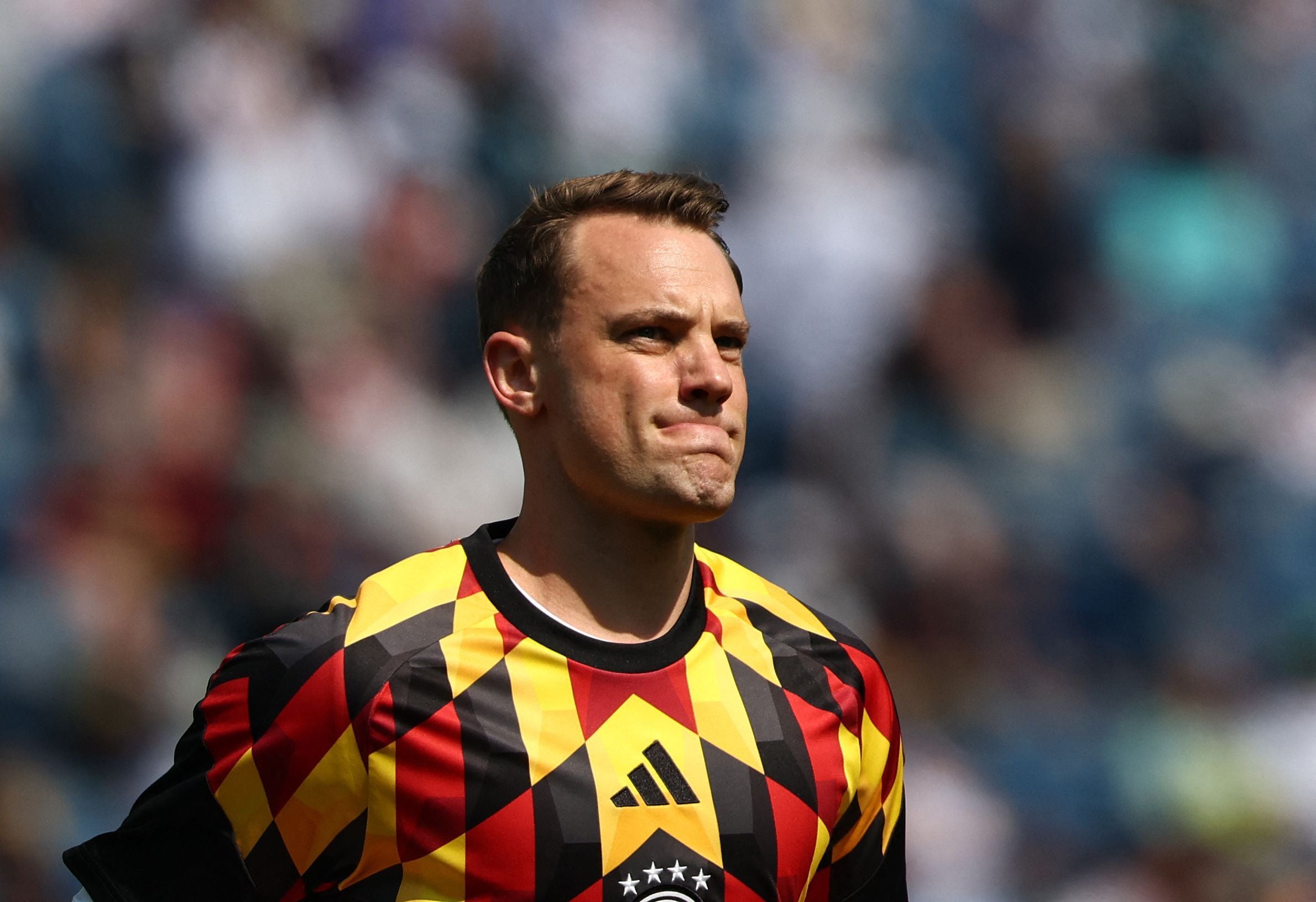 Ein Fußballtorwart im bunt gemusterten Trikot wärmt sich im Stadion auf.