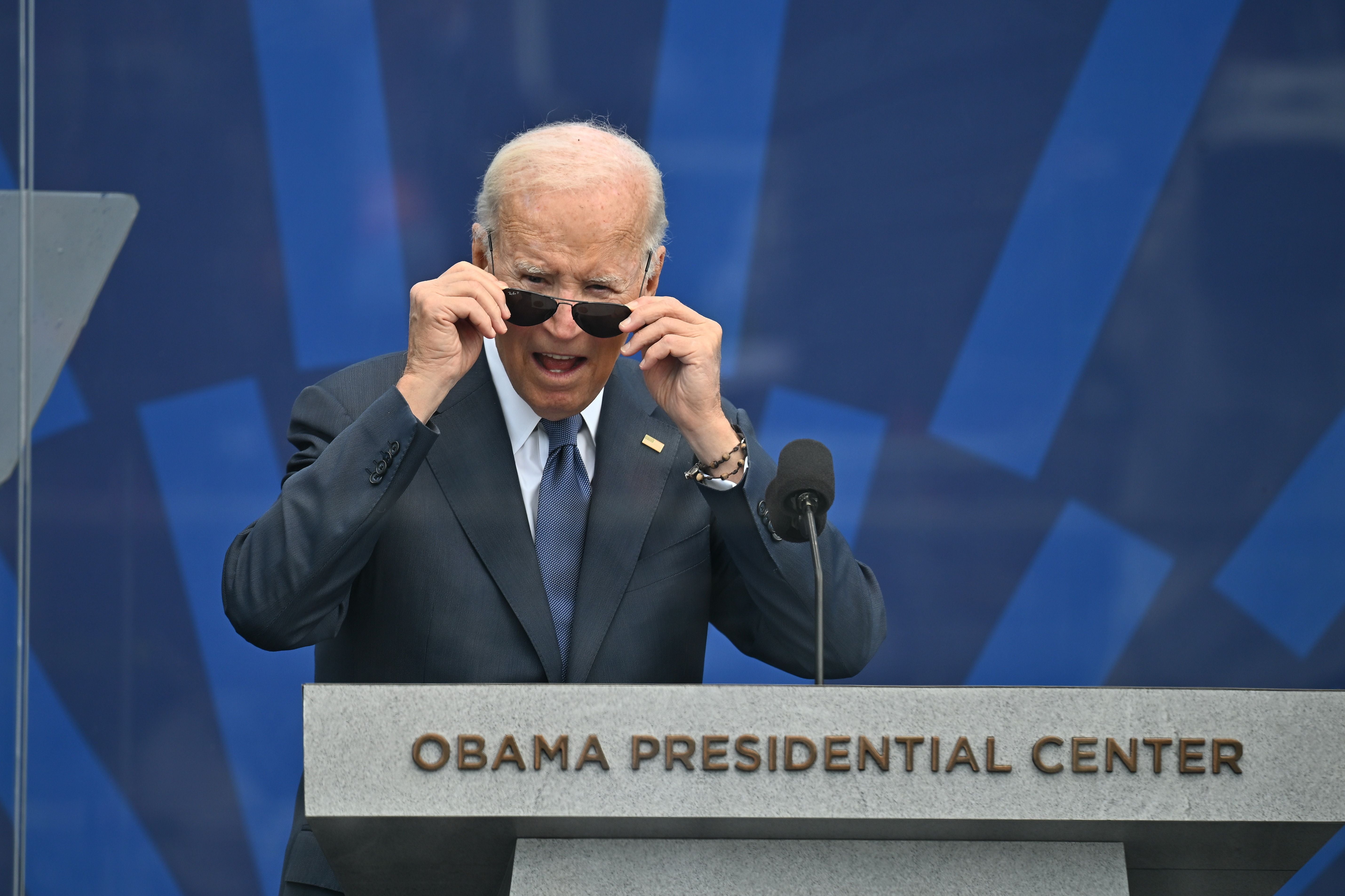 Ein Mann am Rednerpult des Obama Presidential Center hebt seine Sonnenbrille an und spricht.