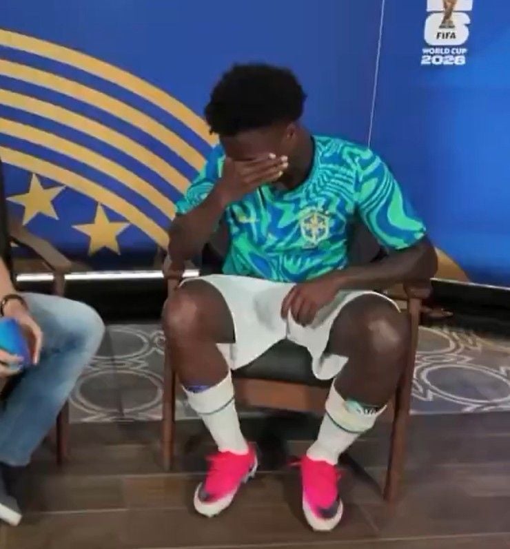 Ein Fußballspieler sitzt auf einem Stuhl und bedeckt sein Gesicht mit der Hand.