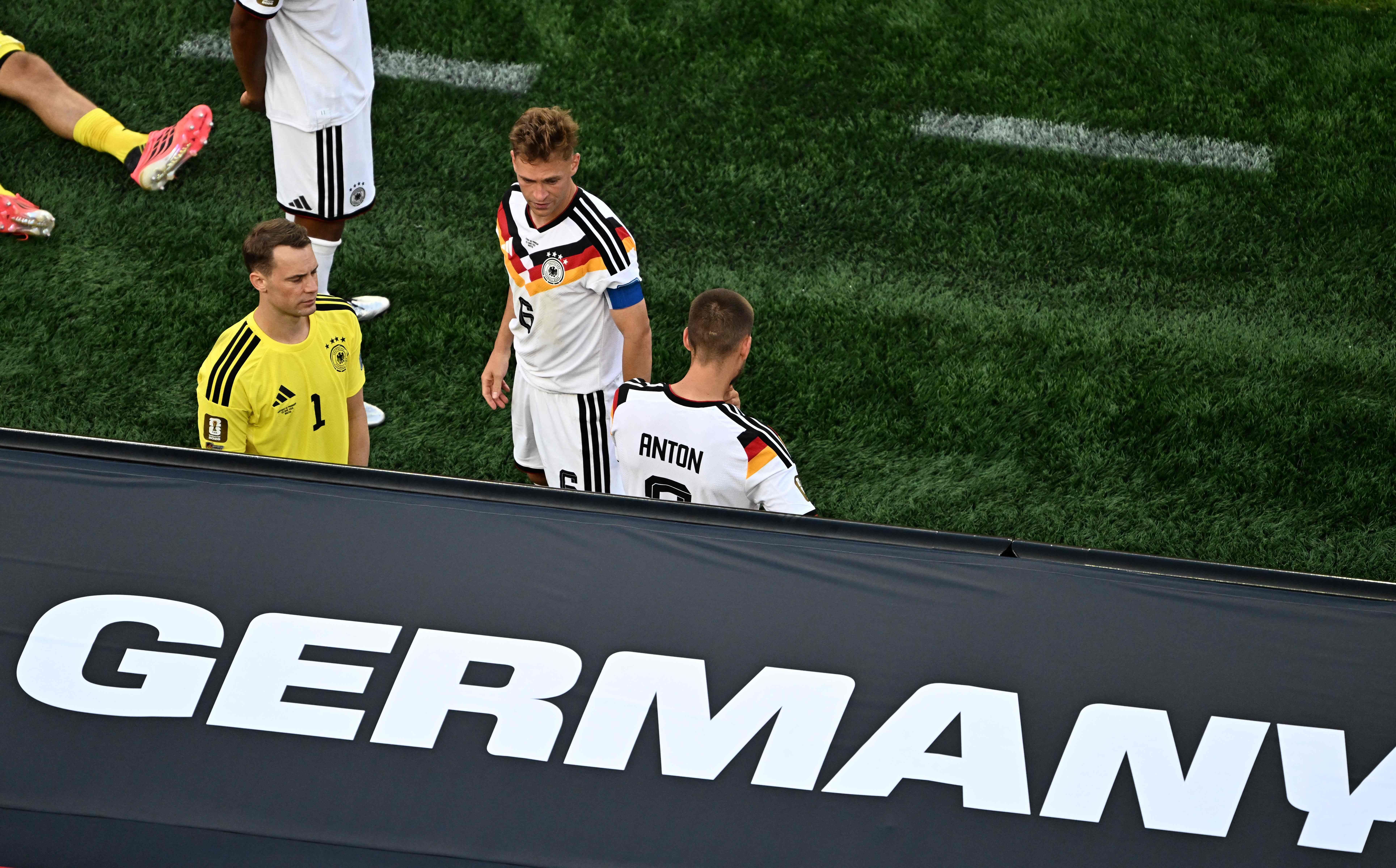 Deutsche Fußballspieler stehen enttäuscht nach einer Niederlage auf dem Spielfeld.