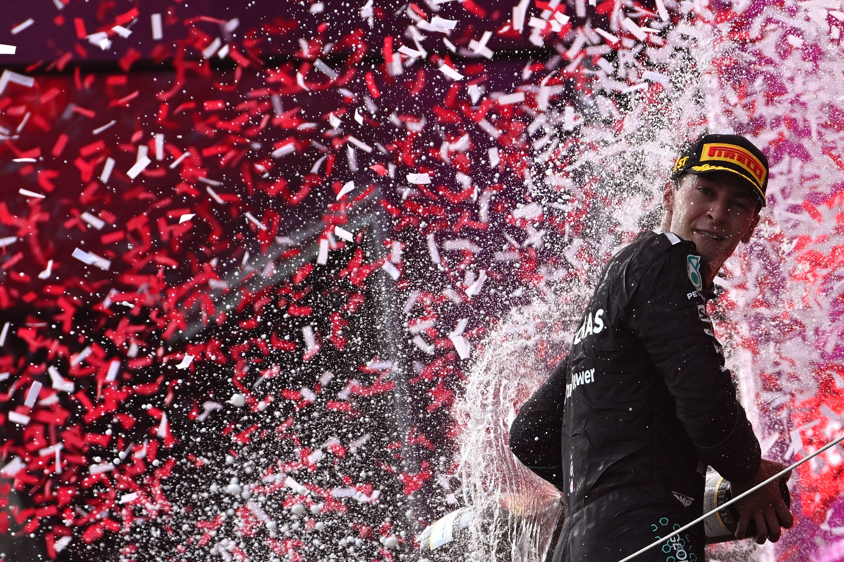 Formel-1-Fahrer feiert auf dem Podium mit Champagner und buntem Konfetti.