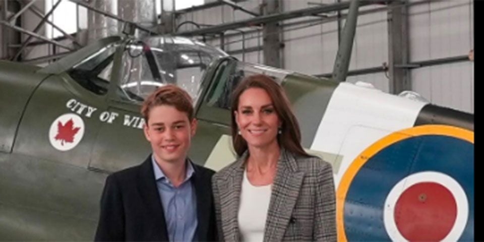 Eine Frau und ein Junge stehen vor einem Militärflugzeug in einem Hangar.