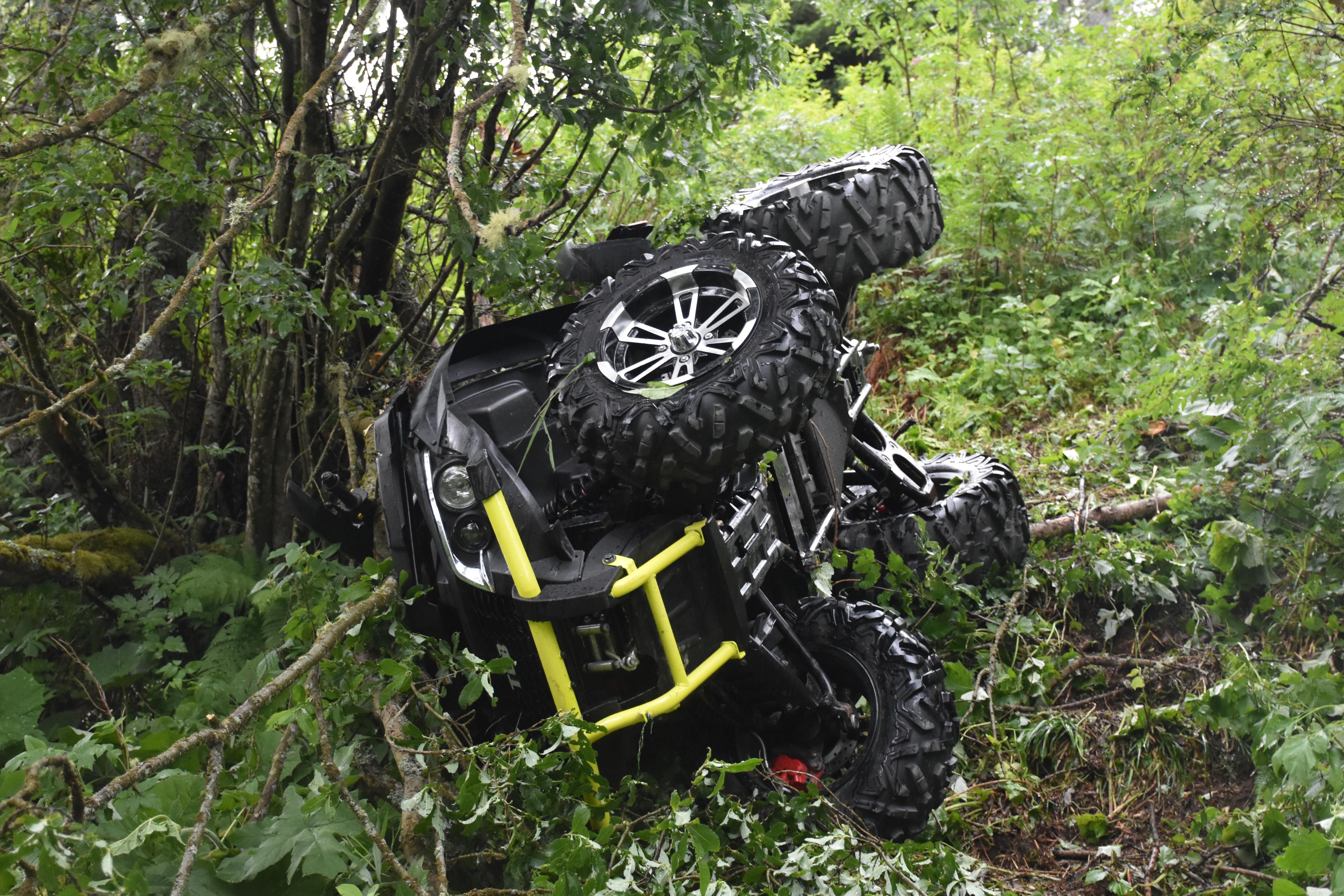 Ein umgestürztes Quad liegt im dichten grünen Unterholz eines Waldes.