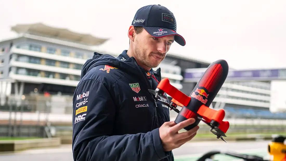 Ein Mann hält eine kleine Drohne mit Red Bull Logo in der Hand.