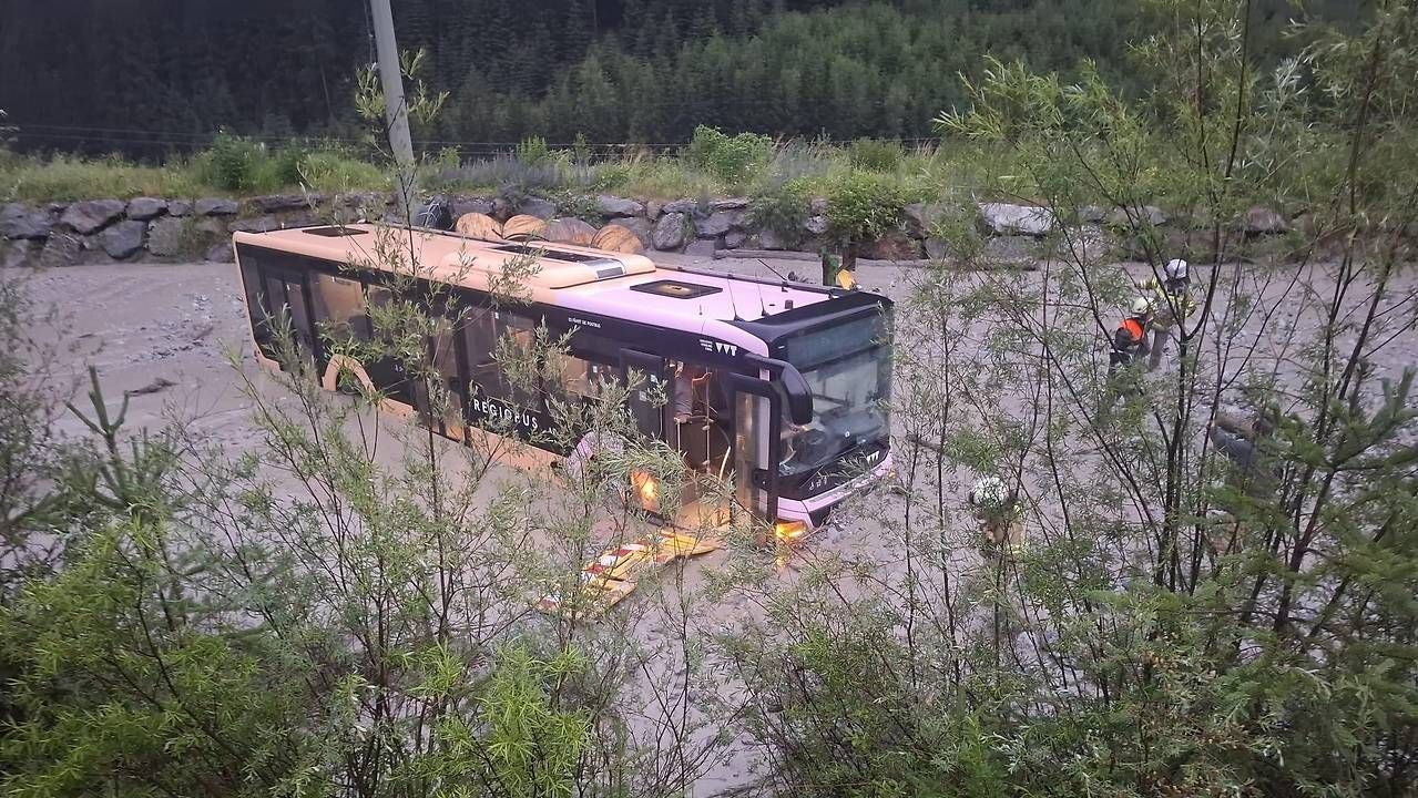 Ein Bus steckt bei Überschwemmung in Schnann im Wasser, Feuerwehrleute sind vor Ort.