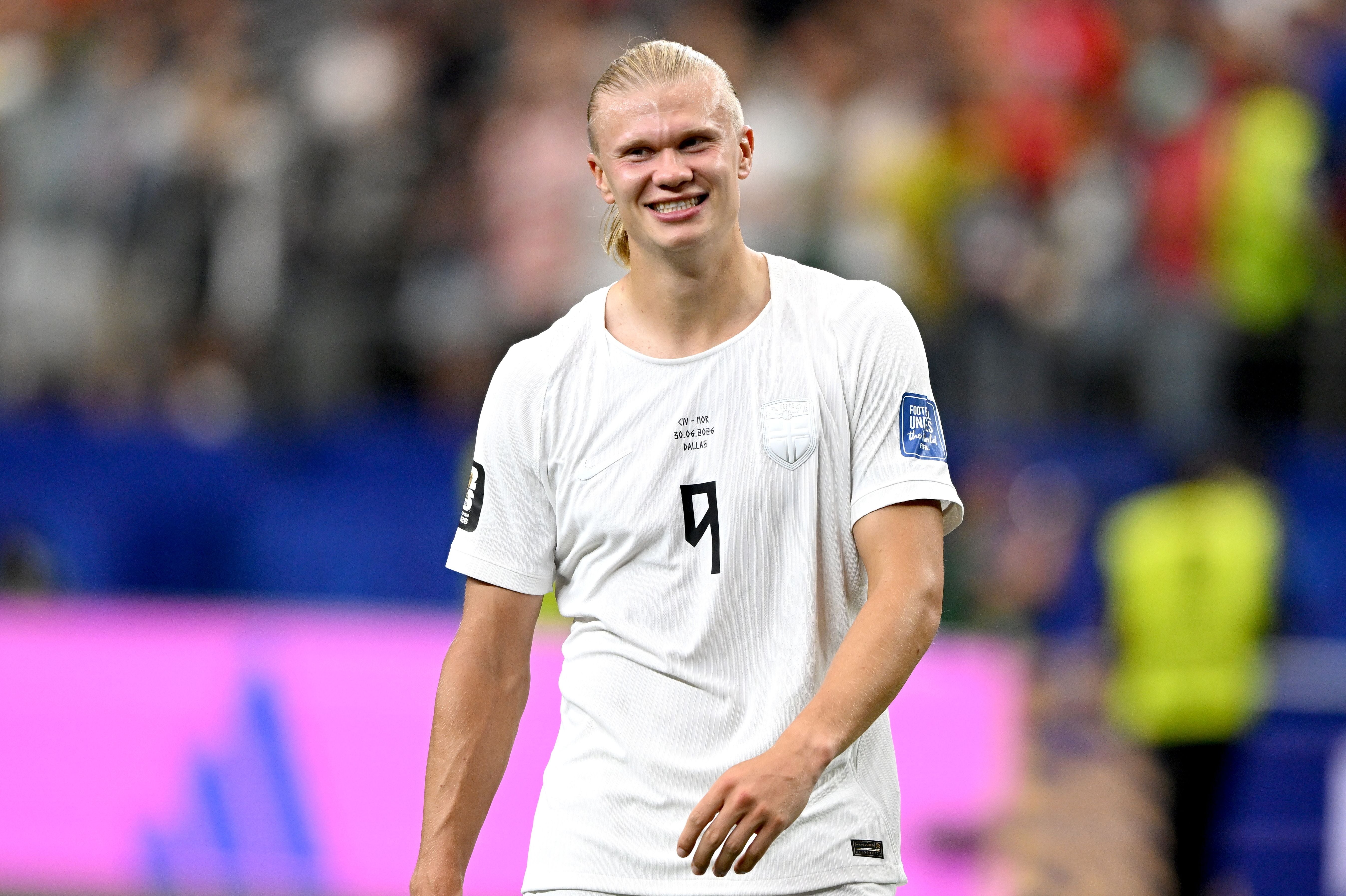 Ein norwegischer Fußballspieler im weißen Trikot lächelt nach einem Spiel auf dem Spielfeld.