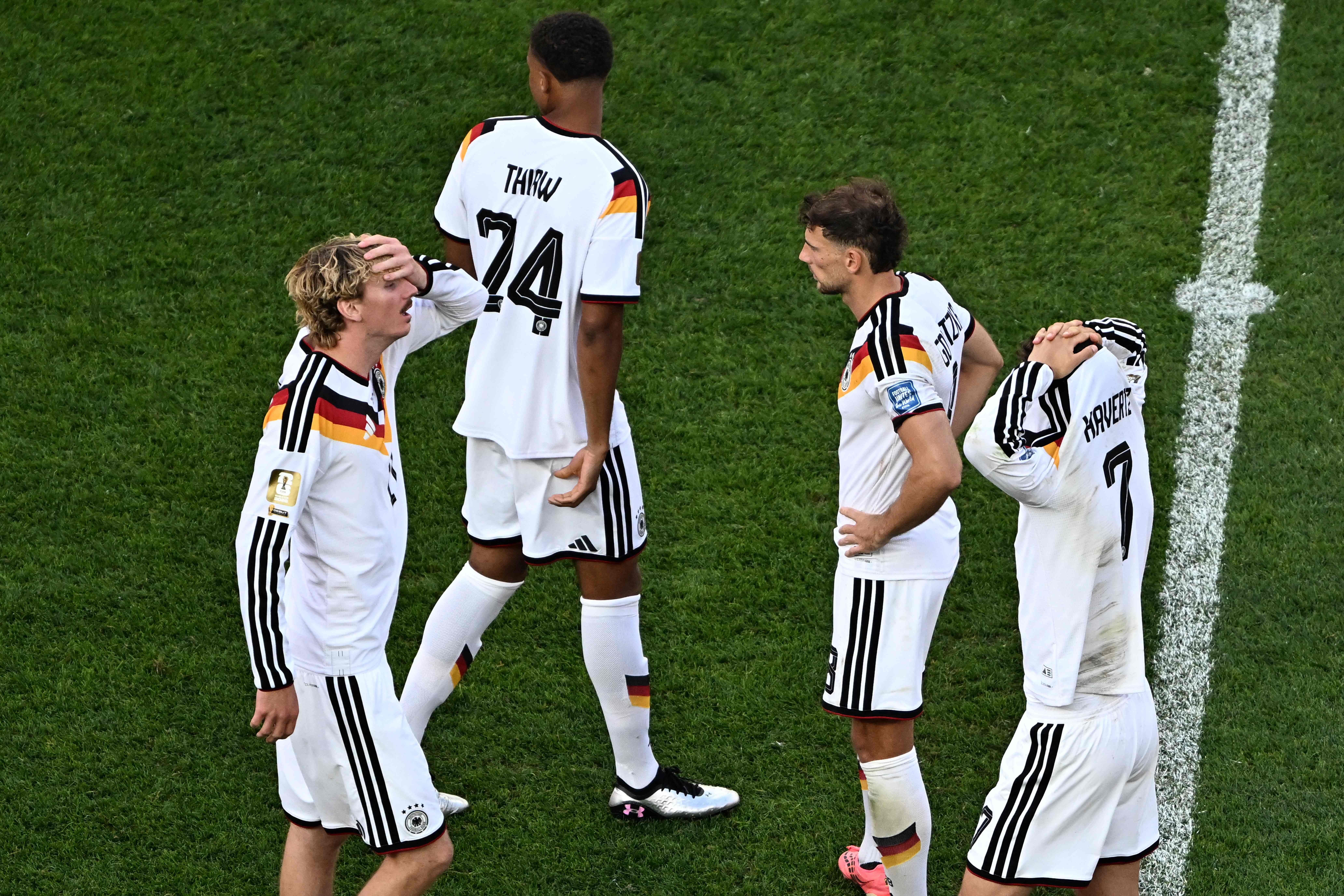 Vier deutsche Fußballspieler stehen enttäuscht nach dem Elfmeterschießen auf dem Spielfeld.