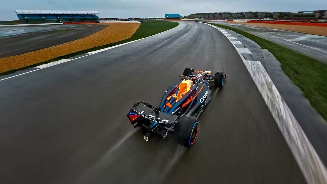 Ein Red Bull Formel-1-Auto fährt auf nasser Rennstrecke, fotografiert aus der Luft.