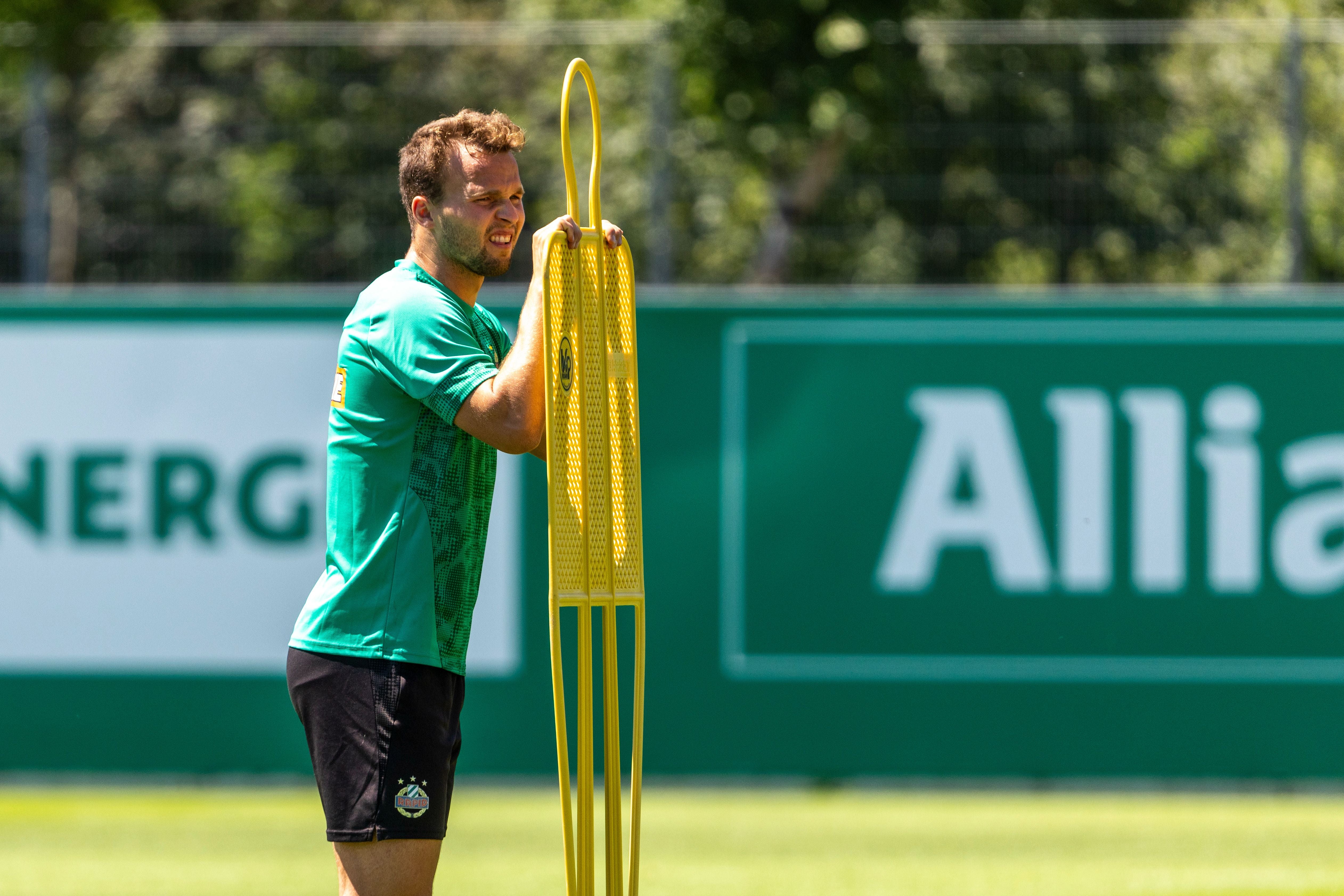 Ein Fußballspieler lehnt beim Training an einer gelben Trainingsfigur auf dem Spielfeld.