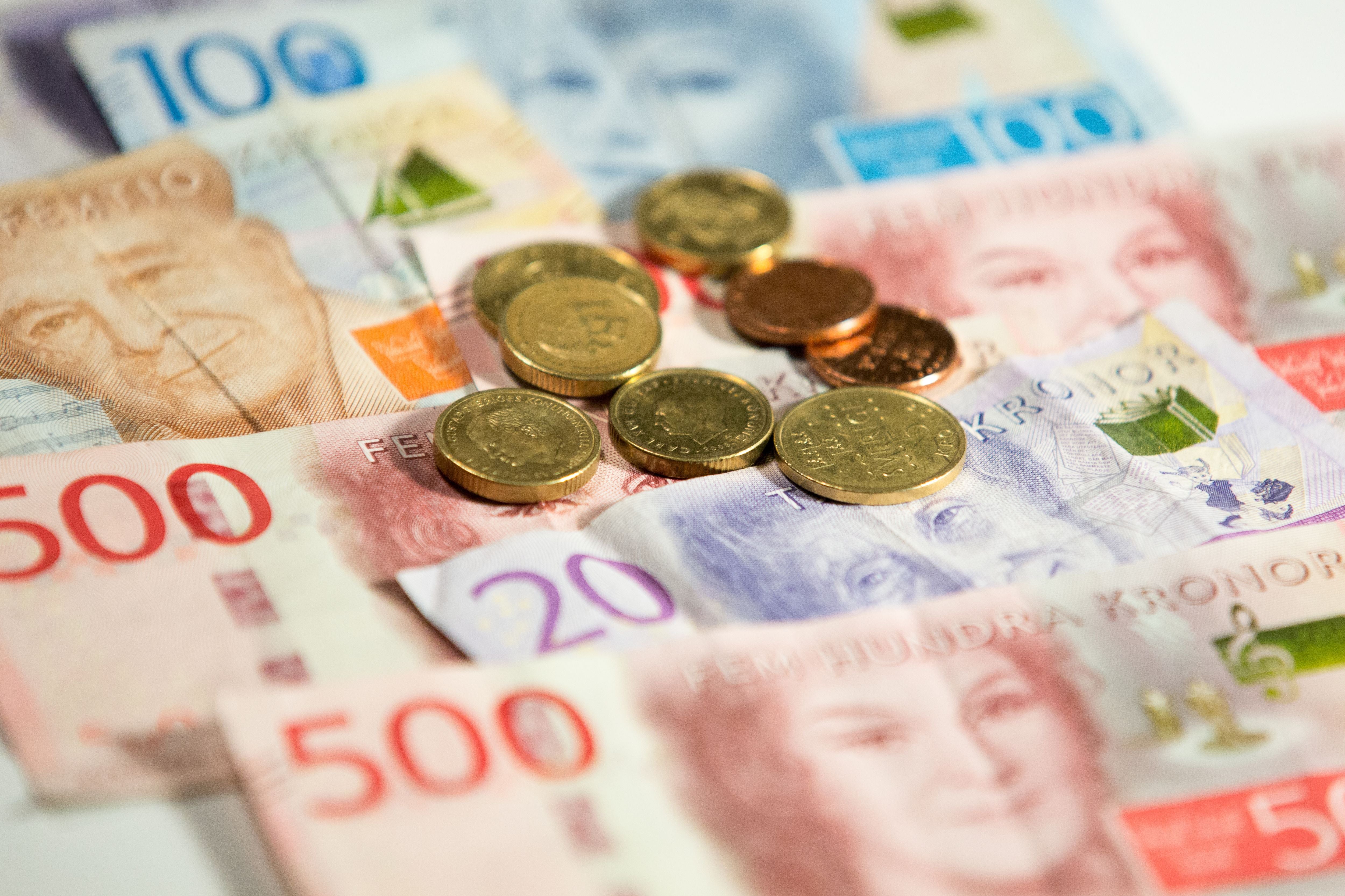 Schwedische Kronen-Banknoten und Münzen liegen gemischt auf einer Oberfläche.