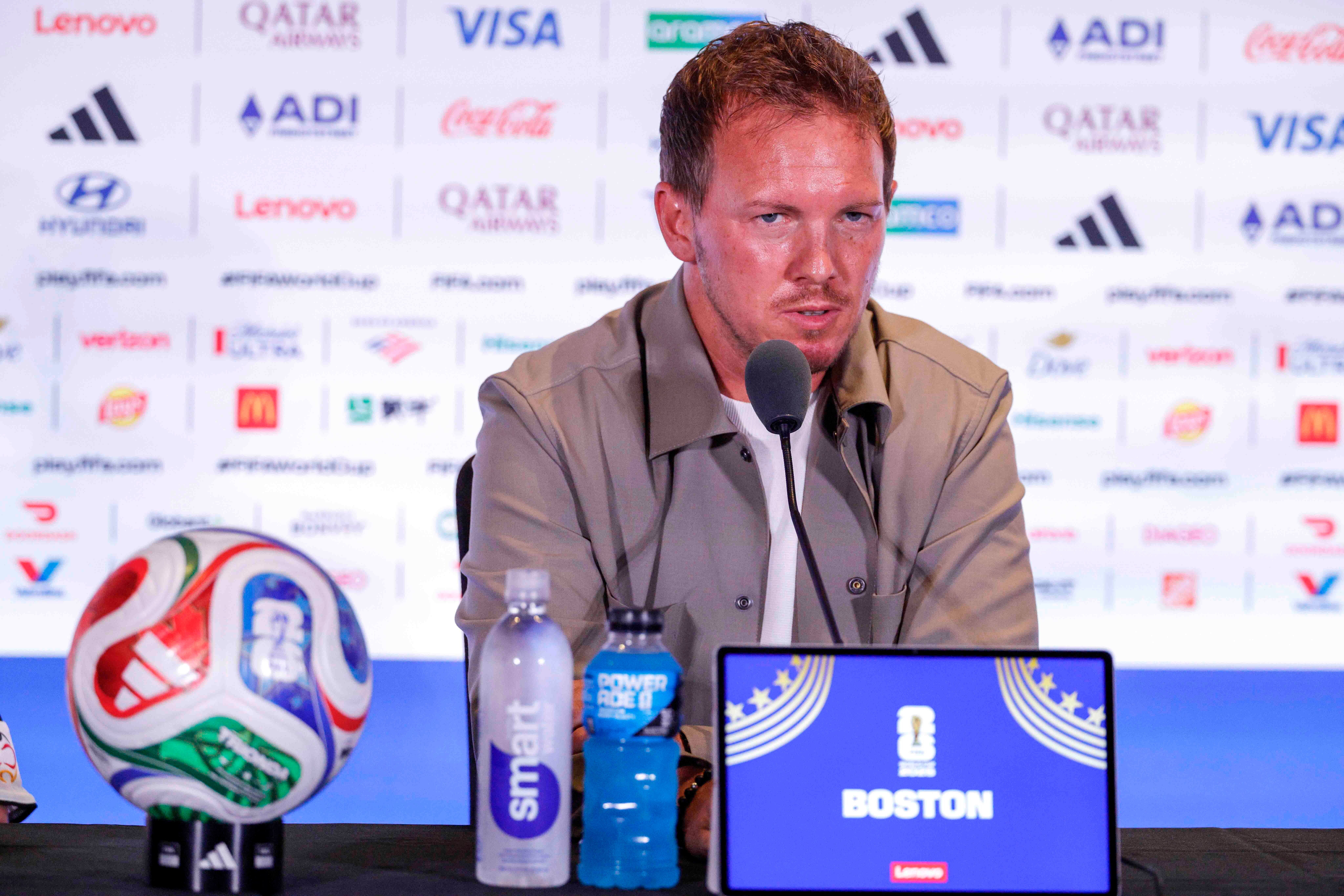 Julian Nagelsmann bei einer Pressekonferenz im WM-Pressebereich in Boston mit Mikrofon und Bildschirm.