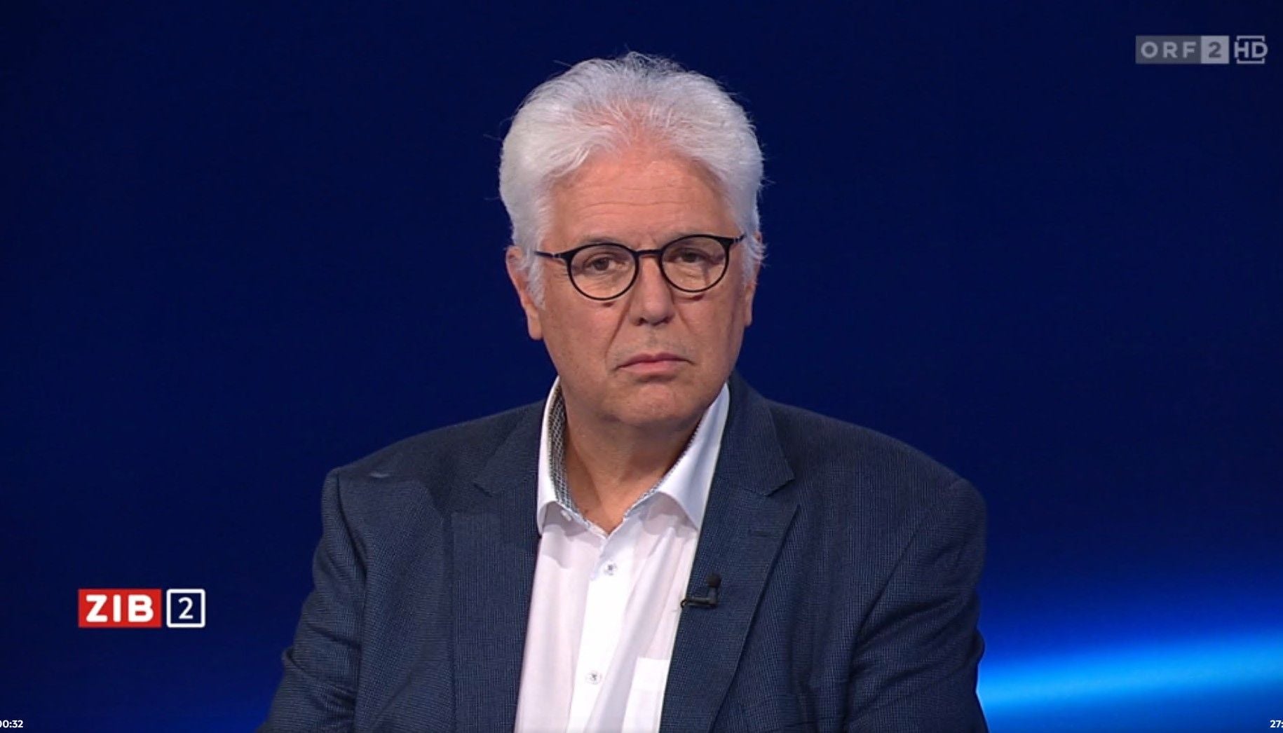 Älterer Mann mit Brille in Anzug und weißem Hemd sitzt im Fernsehstudio von ZIB 2 (ORF).