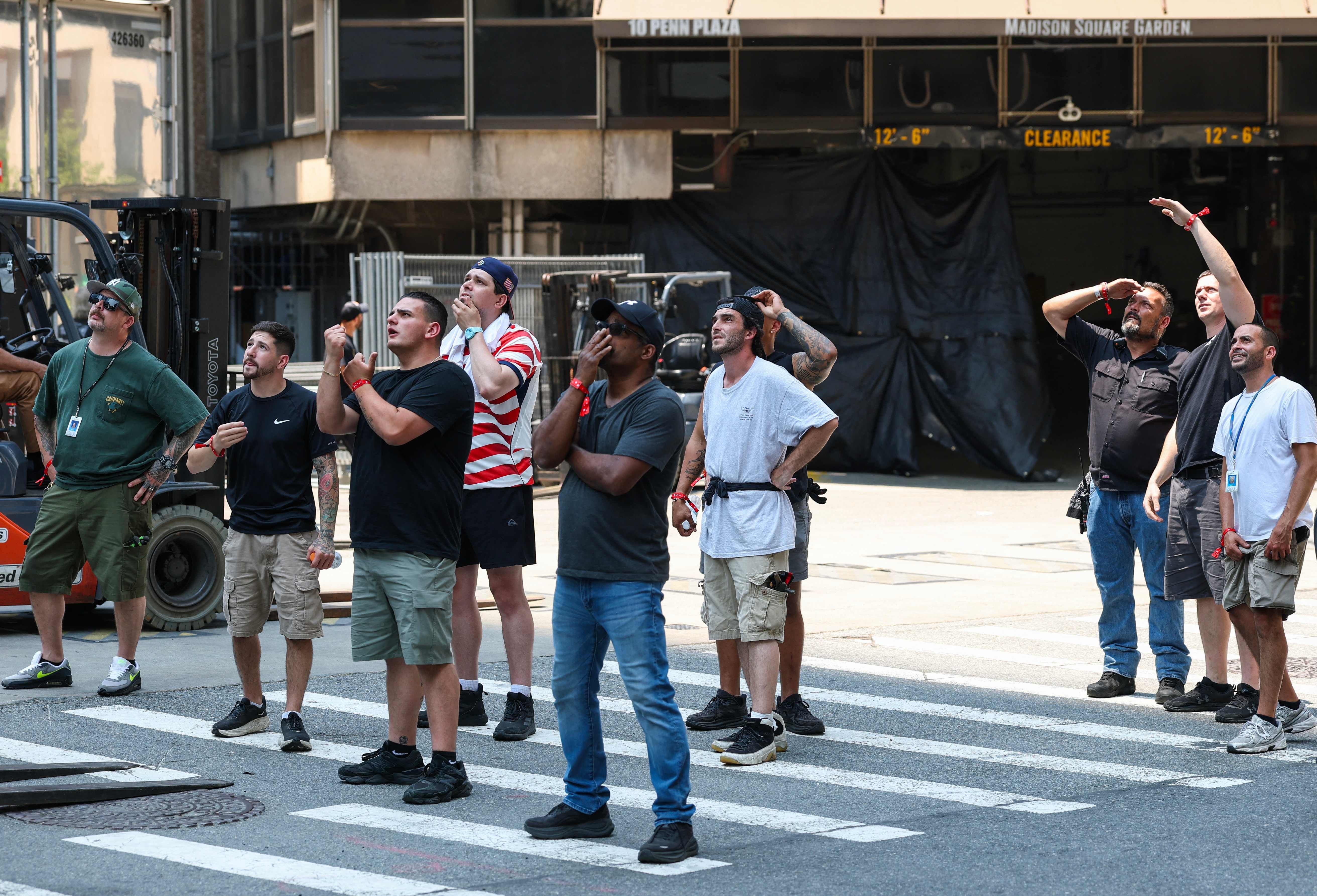 Arbeiter in der Nähe des Madison Square Garden halten an und blicken zum Empire State Building in New York auf. US-Medien veröffentlichten Videos, die zeigen, wie zwei Personen auf die Spitze des Empire State Building kletterten und ein Banner entrollten, auf dem anscheinend zu lesen war: "Wenn die Macht der Liebe die Liebe zur Macht besiegt, kennt die Welt Frieden."