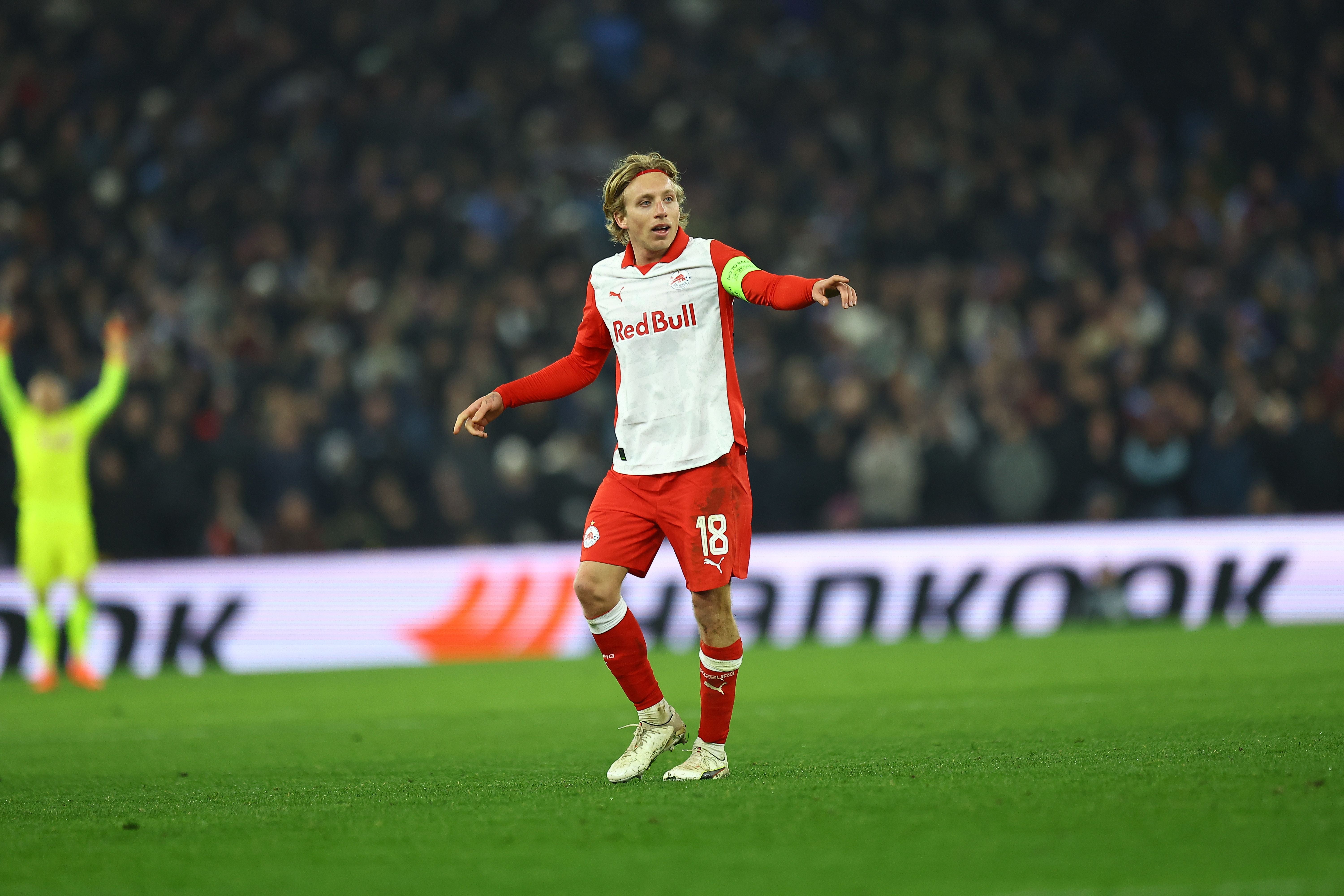 Ein Fußballspieler von Red Bull Salzburg steht auf dem Spielfeld und zeigt mit dem Arm zur Seite.