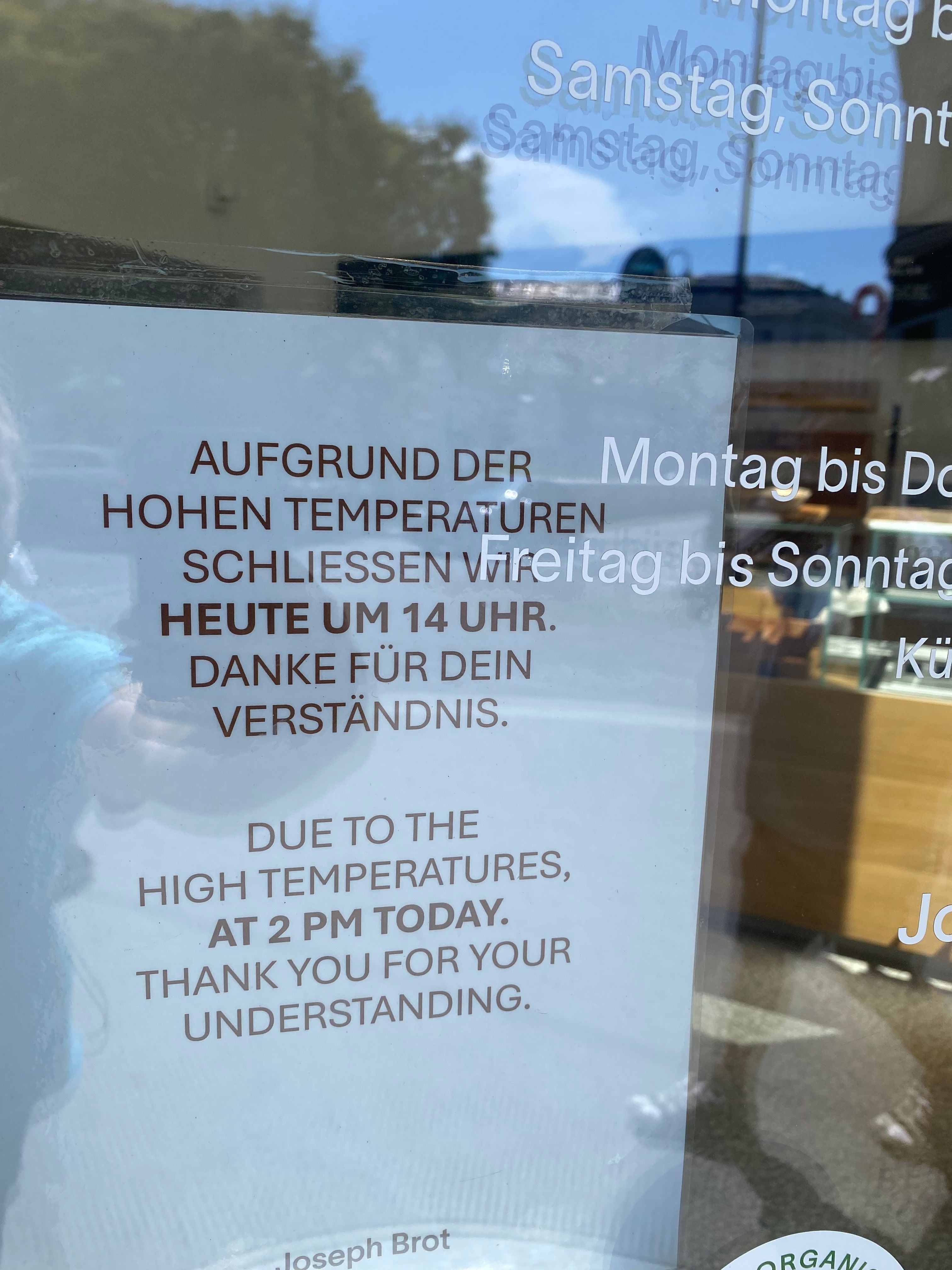 Aushang an einer Tür: Wegen hoher Temperaturen heute um 14 Uhr geschlossen, auf Deutsch und Englisch.