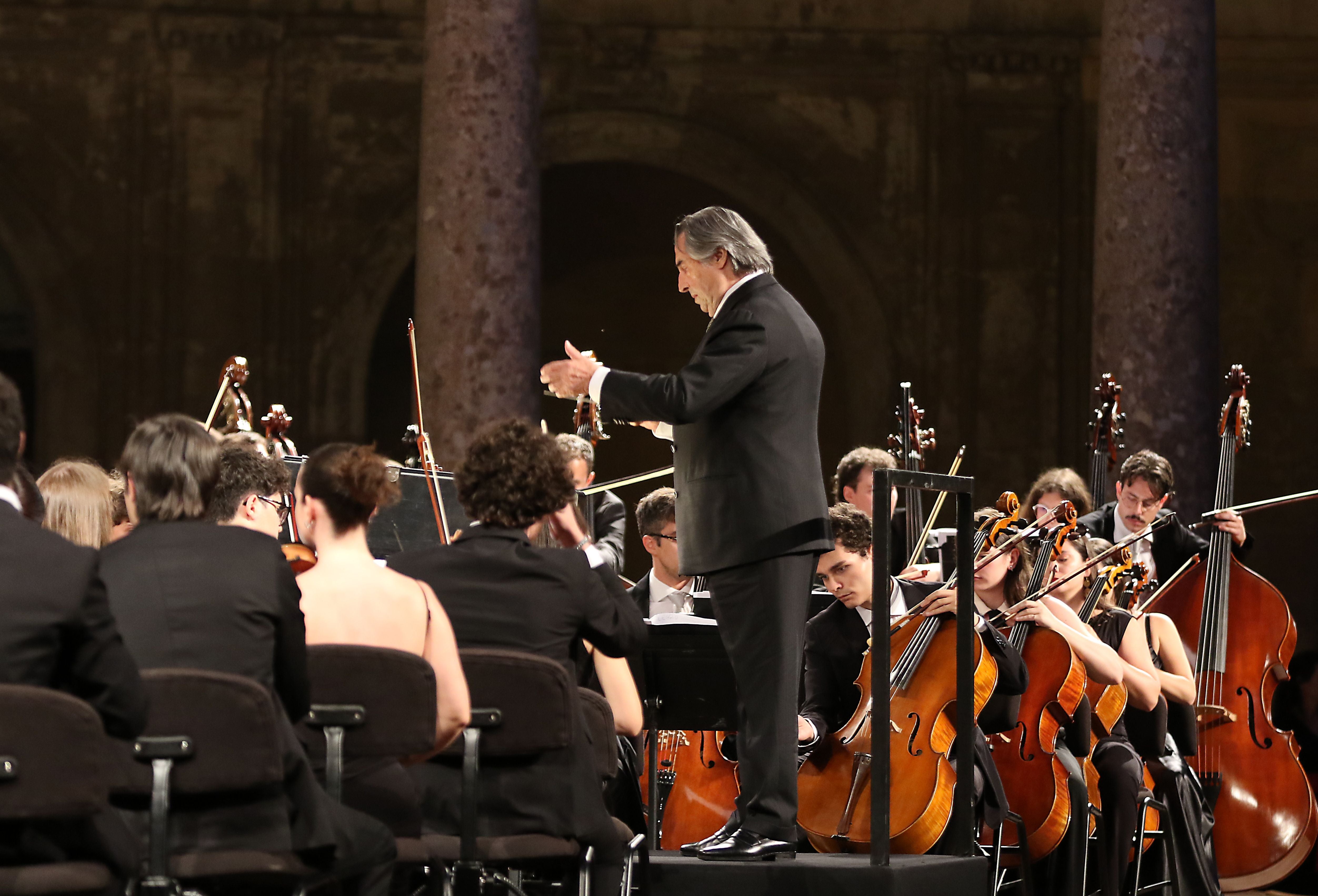 Ein Orchester spielt unter der Leitung eines Dirigenten in einer festlichen Halle.