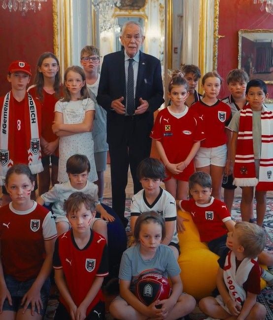 Bundespräsident Van der Bellen mit einer Gruppe Kinder im Fußballtrikot in der Hofburg.