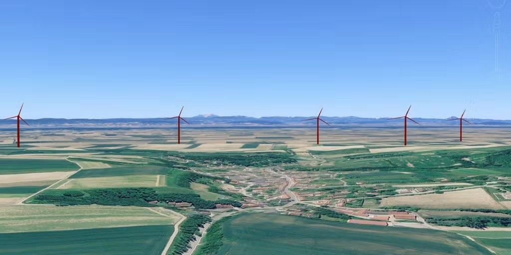 Landschaft mit fünf Windkraftanlagen und Feldern unter blauem Himmel.