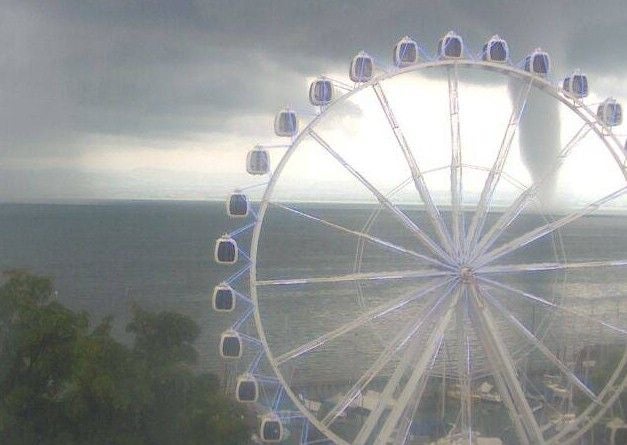 Großes Riesenrad am Bodensee, im Hintergrund eine Wasserhose unter dunklen Wolken.