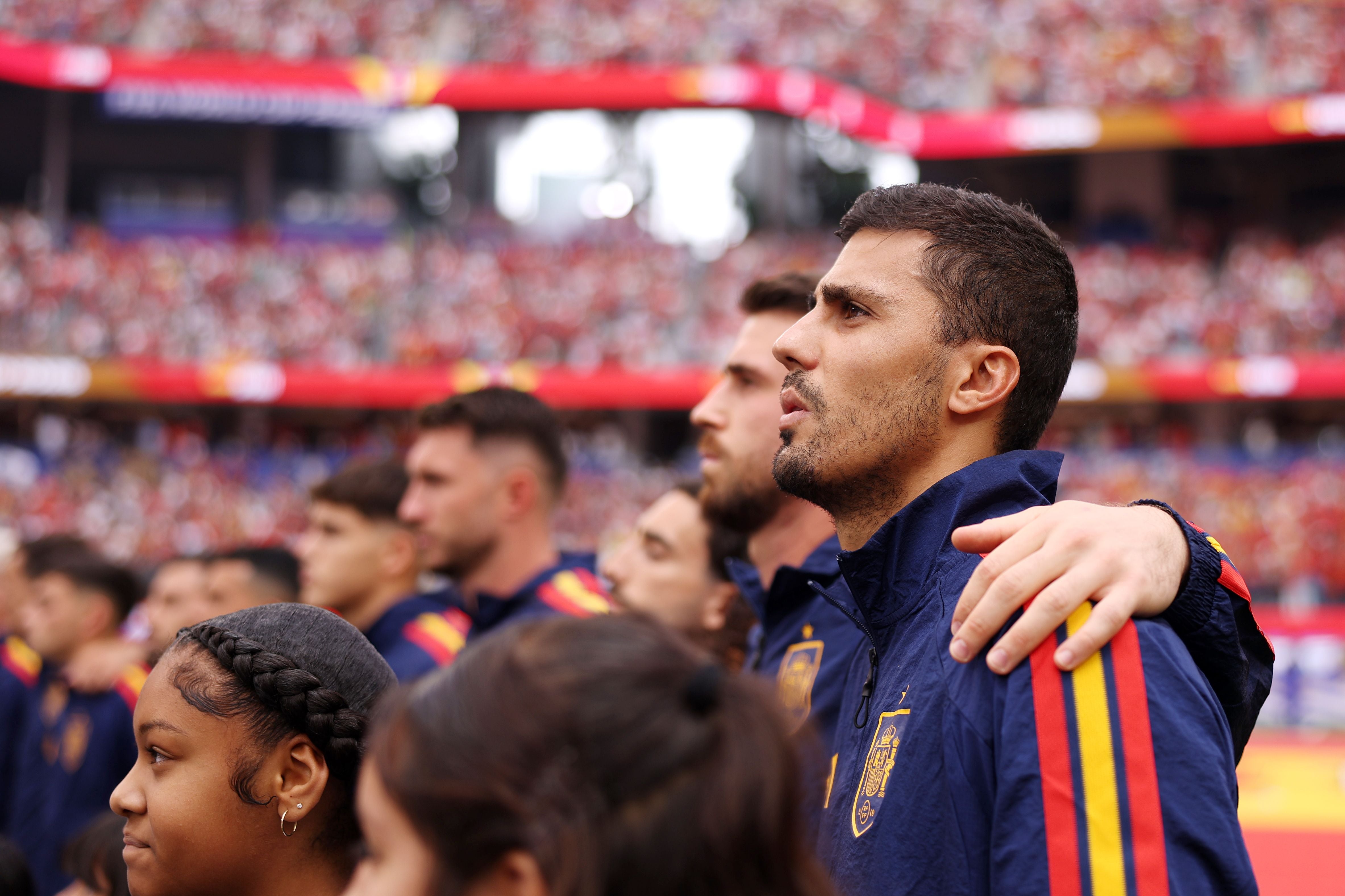Spanische Fußballspieler stehen Arm in Arm während der Nationalhymne im Stadion.
