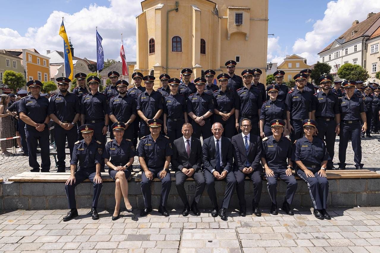 Gruppenfoto von Polizisten und Offiziellen vor dem Retzer Rathaus bei sonnigem Wetter.