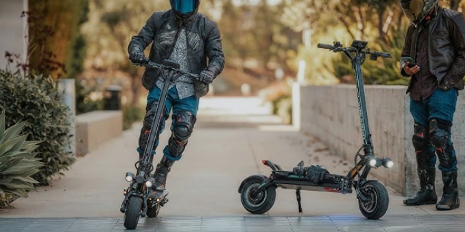 Zwei Personen mit Schutzkleidung stehen neben schnellen E-Scootern auf einem Gehweg.