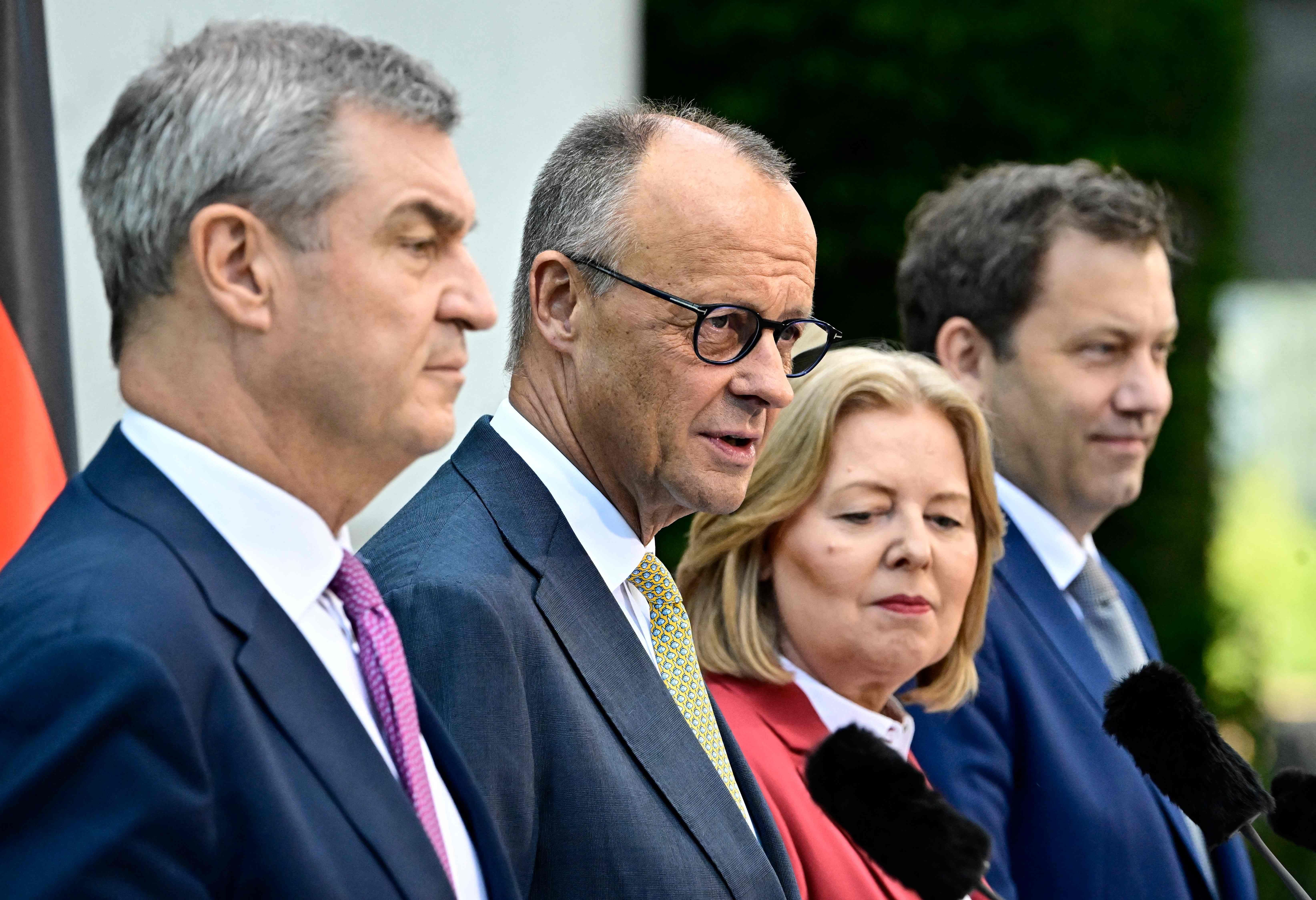 Vier Politiker stehen nebeneinander bei einer Pressekonferenz im Garten der Berliner Kanzlei.