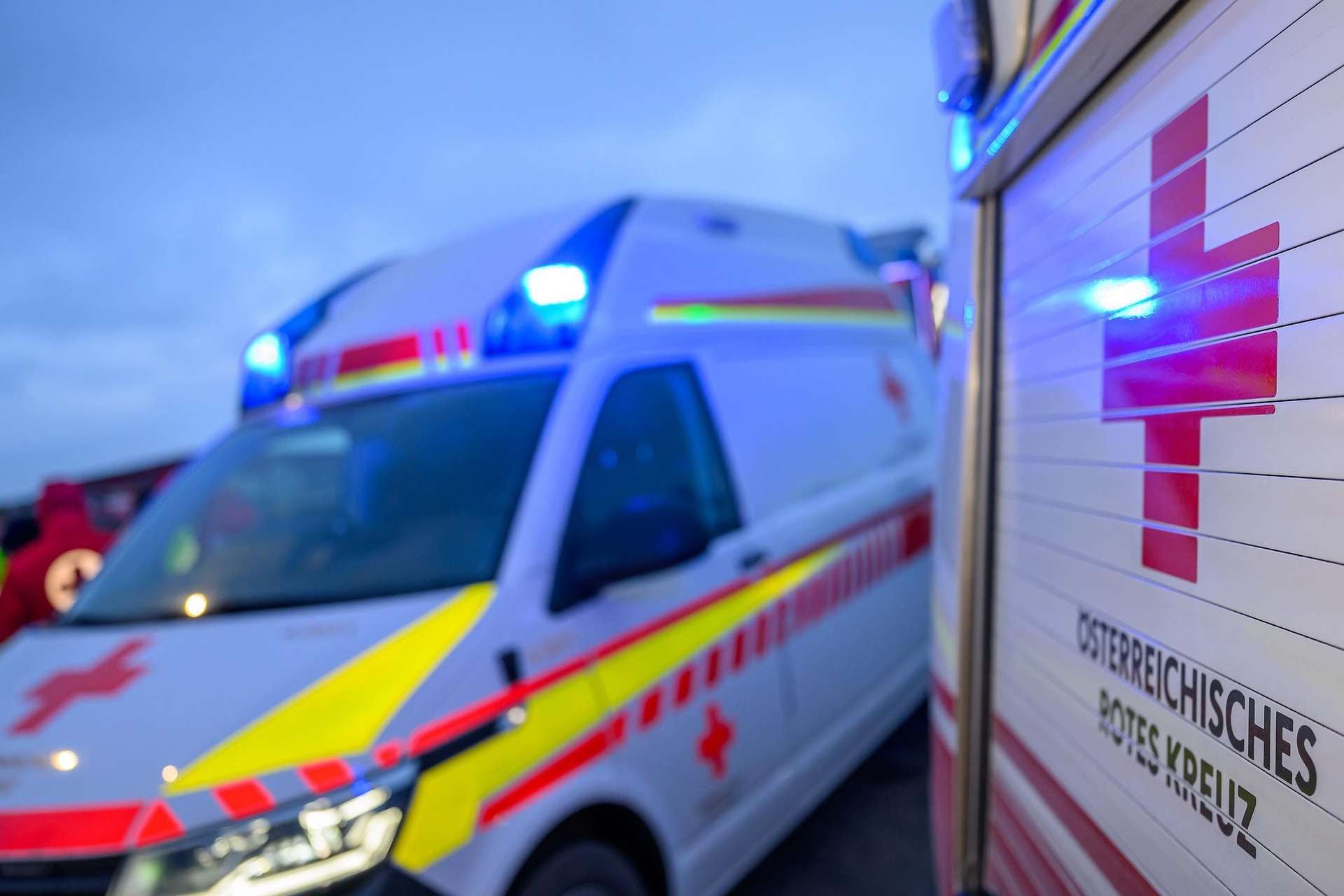 Zwei Rettungsfahrzeuge des Österreichischen Roten Kreuzes mit eingeschaltetem Blaulicht.