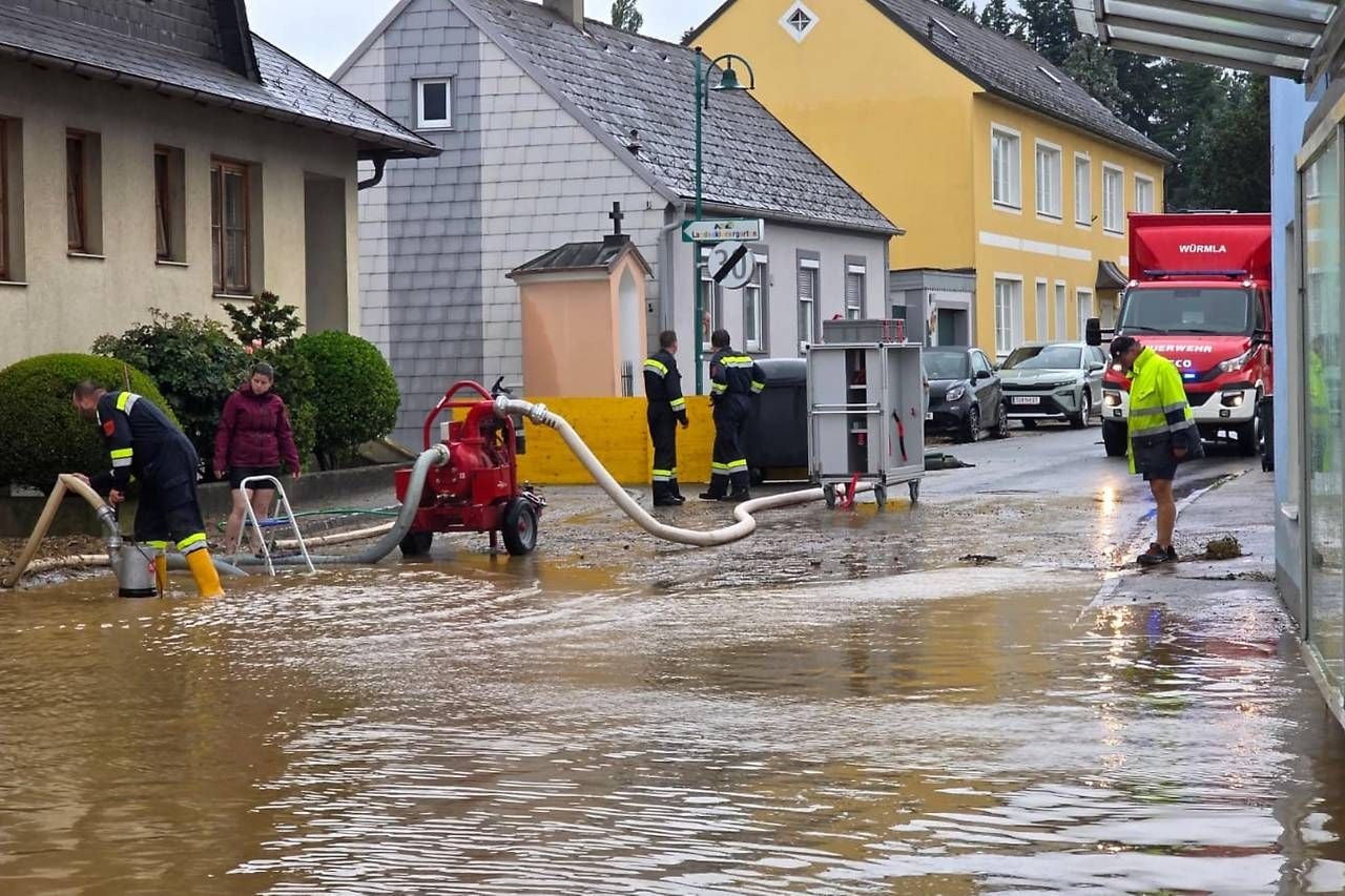 Einsatzkräfte pumpen Wasser aus überfluteter Straße in Würmla nach starkem Unwetter.