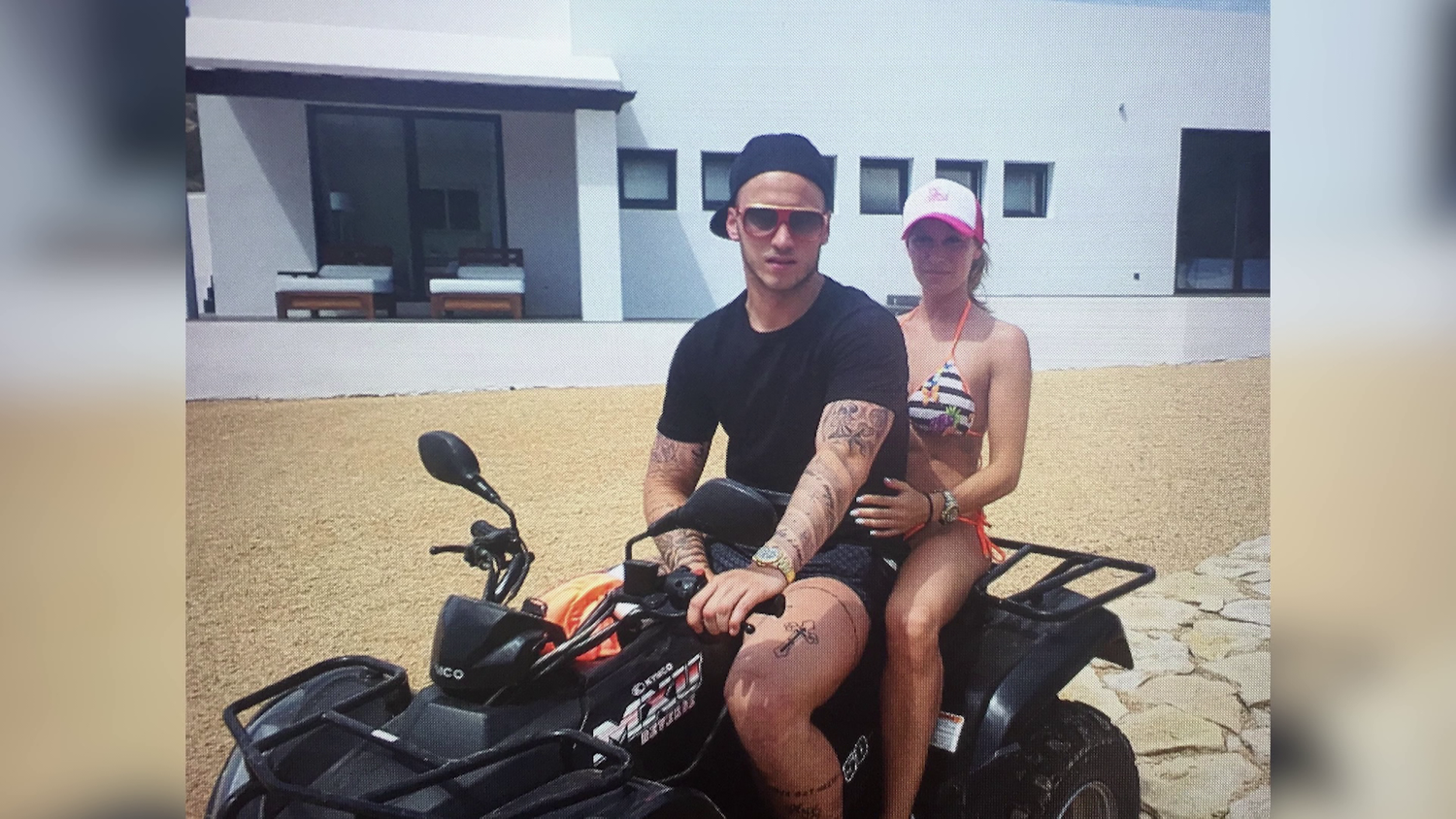 Ein Mann und eine Frau sitzen auf einem Quad vor einem modernen weißen Gebäude.