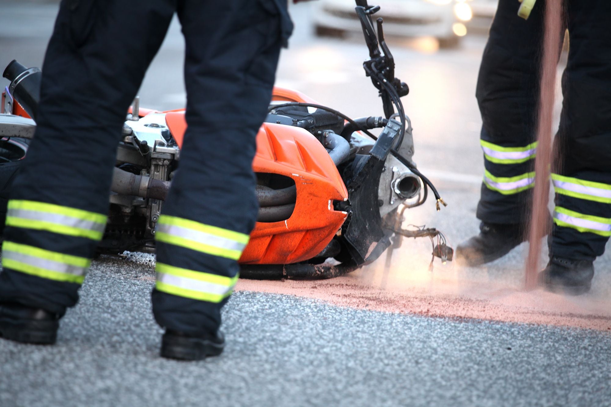 Feuerwehrleute sichern nach einem Motorradunfall eine Unfallstelle auf der Straße.