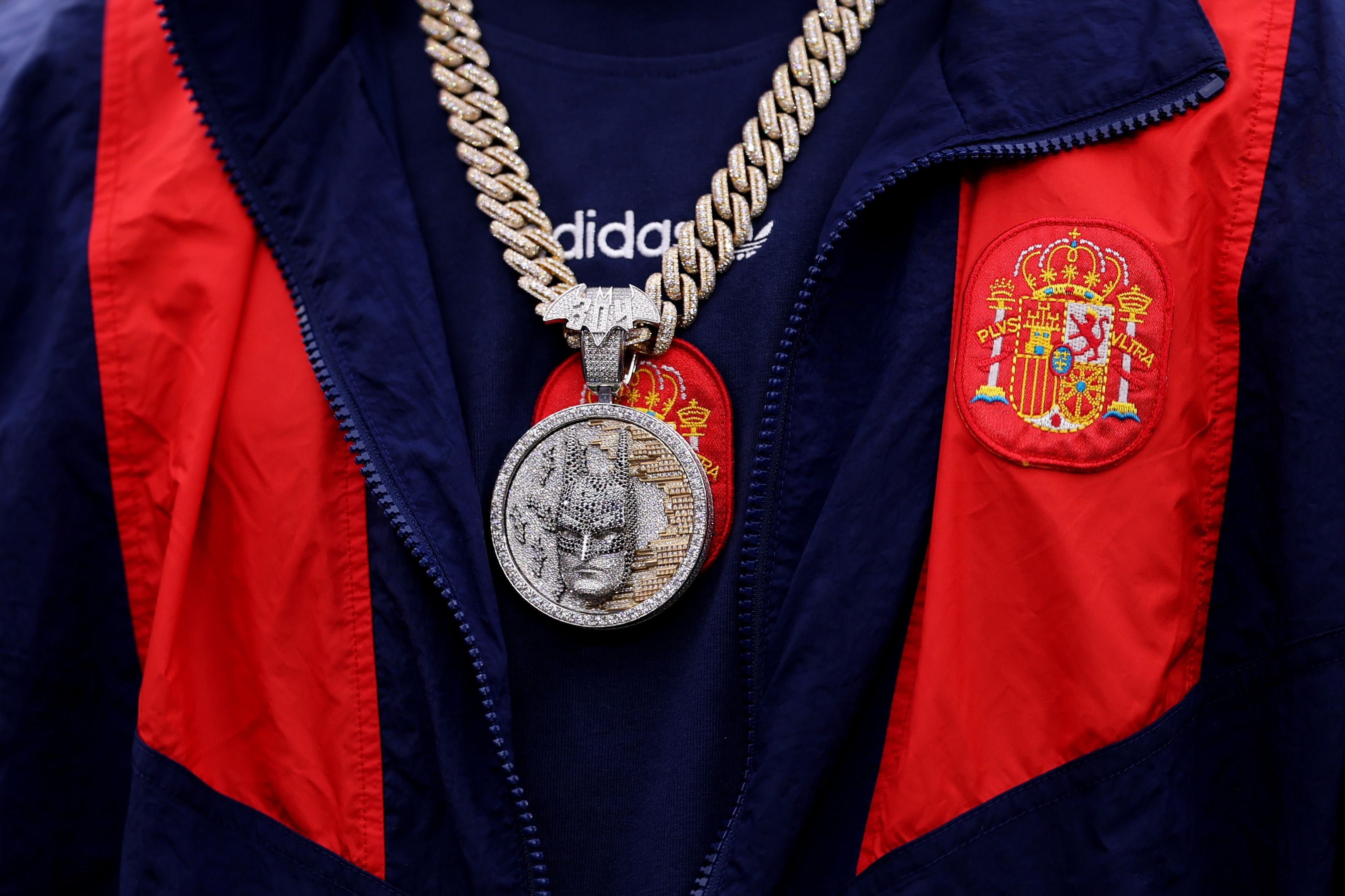 Eine goldene Kette mit großem, diamantbesetztem Anhänger über einem Spanien-Trikot.