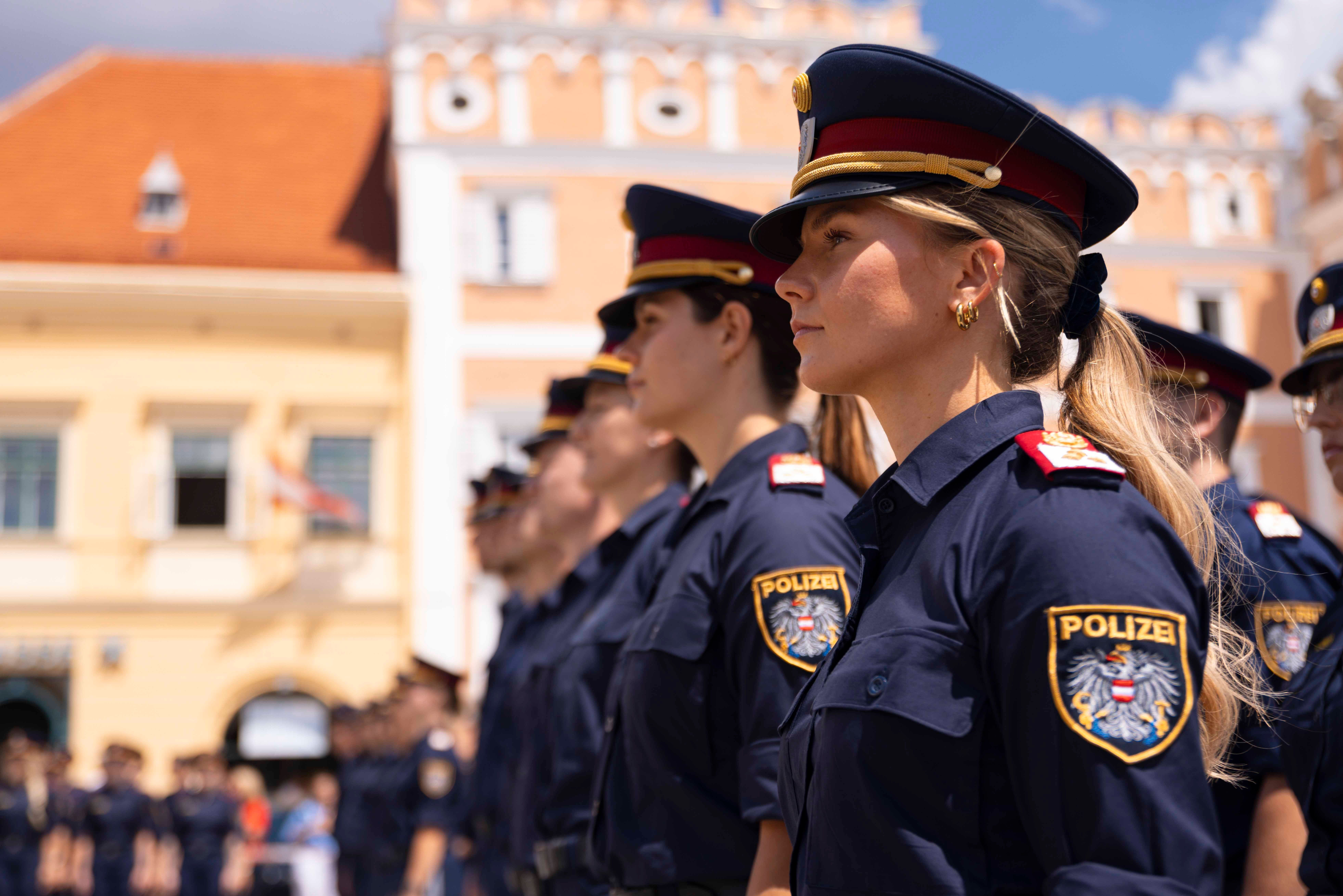 Mehrere Polizistinnen stehen bei einer Angelobung in Uniform in einer Reihe im Freien.