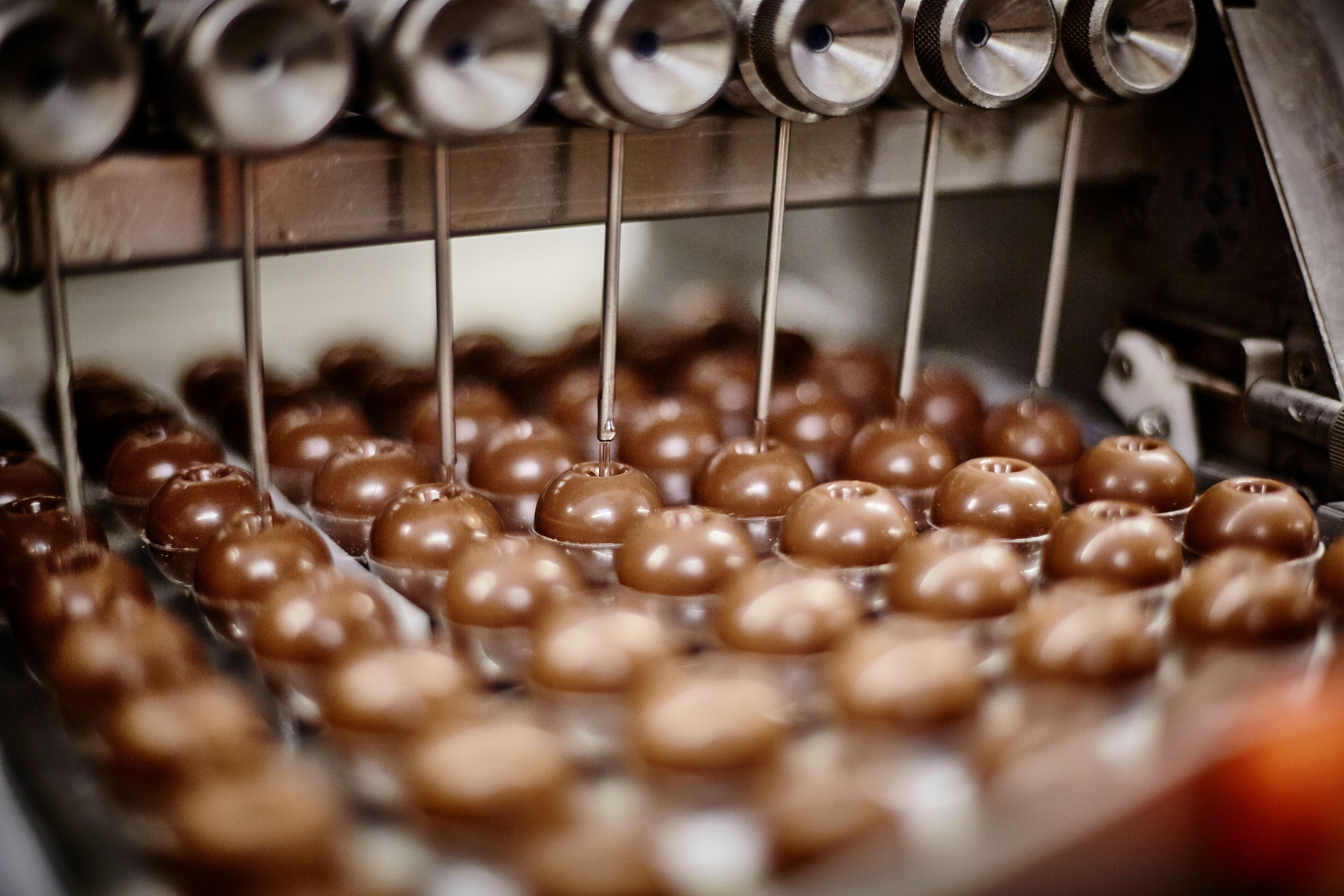 Industrielle Maschine befüllt Pralinen mit flüssiger Schokolade.
