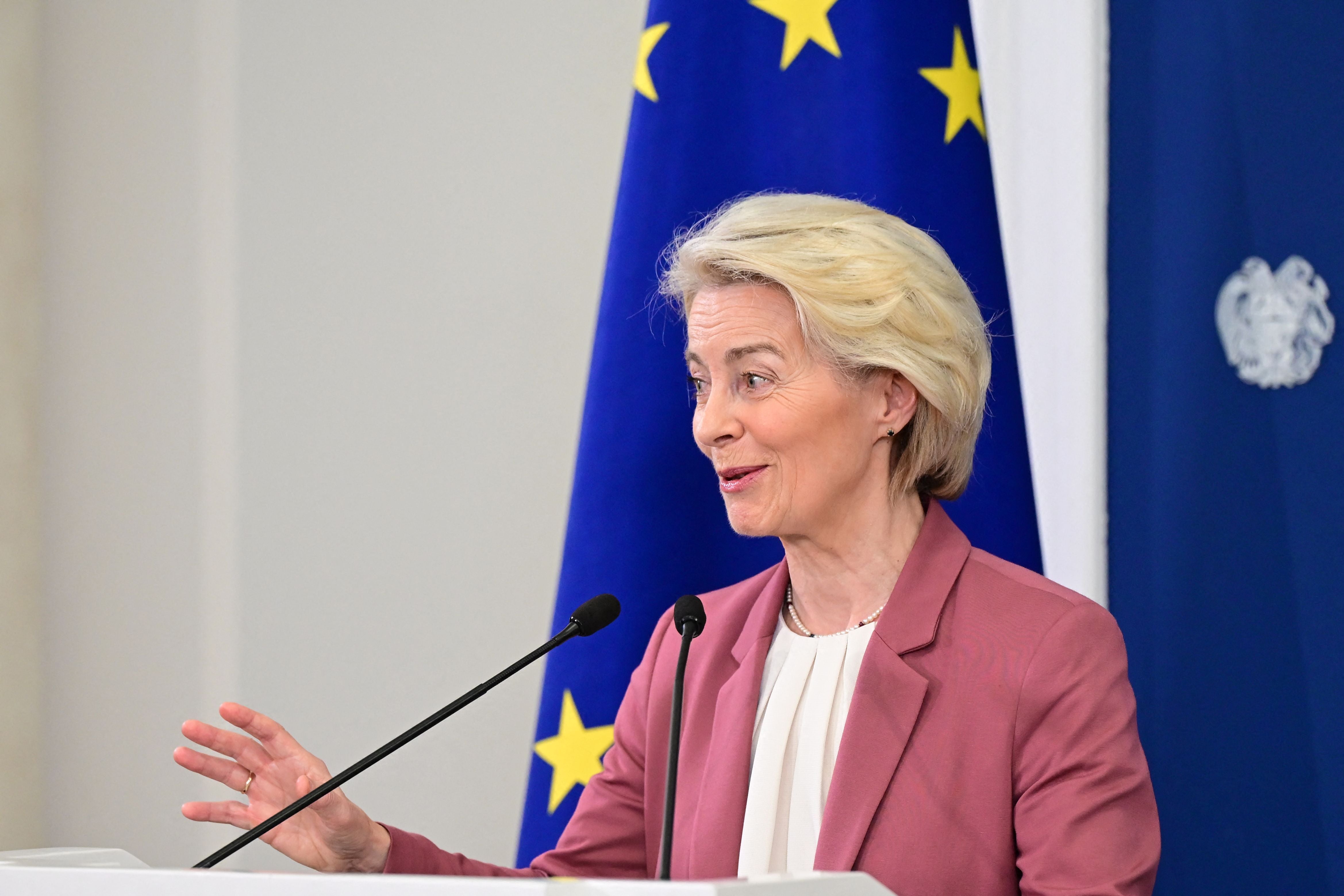 Frau spricht auf einer Pressekonferenz vor EU-Flagge und Mikrofonen.