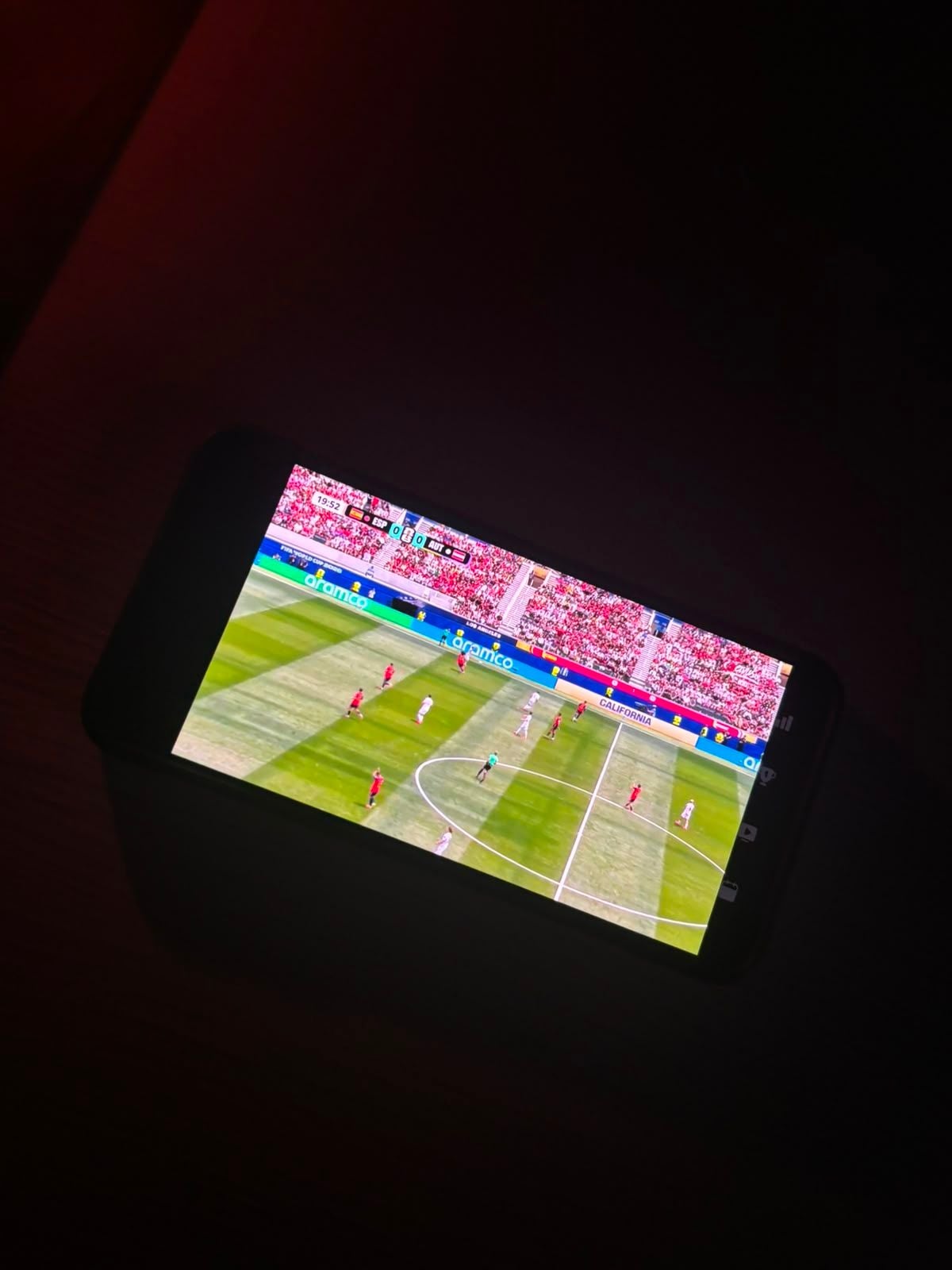 Ein Fußballspiel läuft auf einem Smartphone mit dunkler Umgebung wegen Stromausfall.