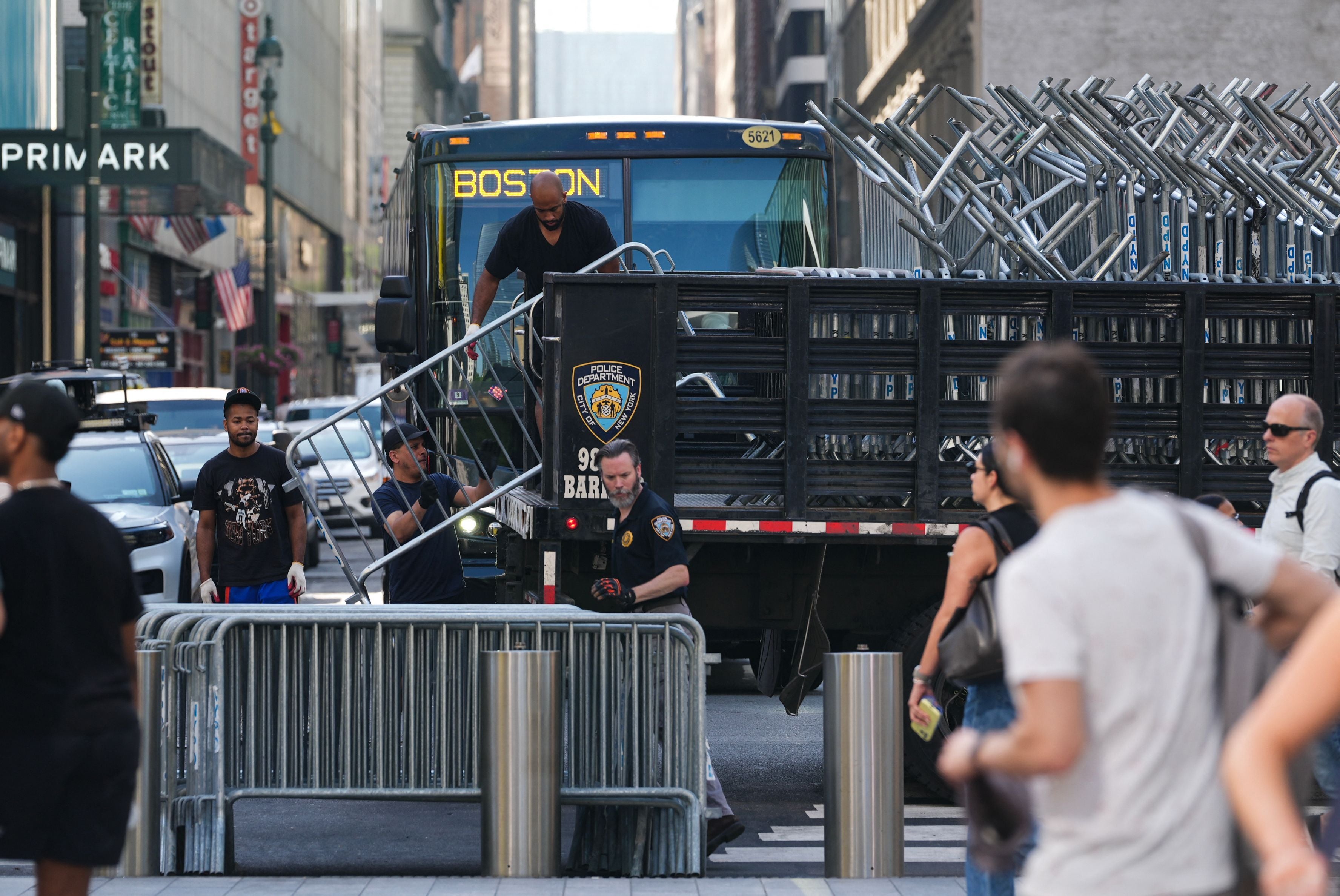 Arbeiter laden Polizeibarrieren von einem LKW in einer belebten Straße in New York ab.