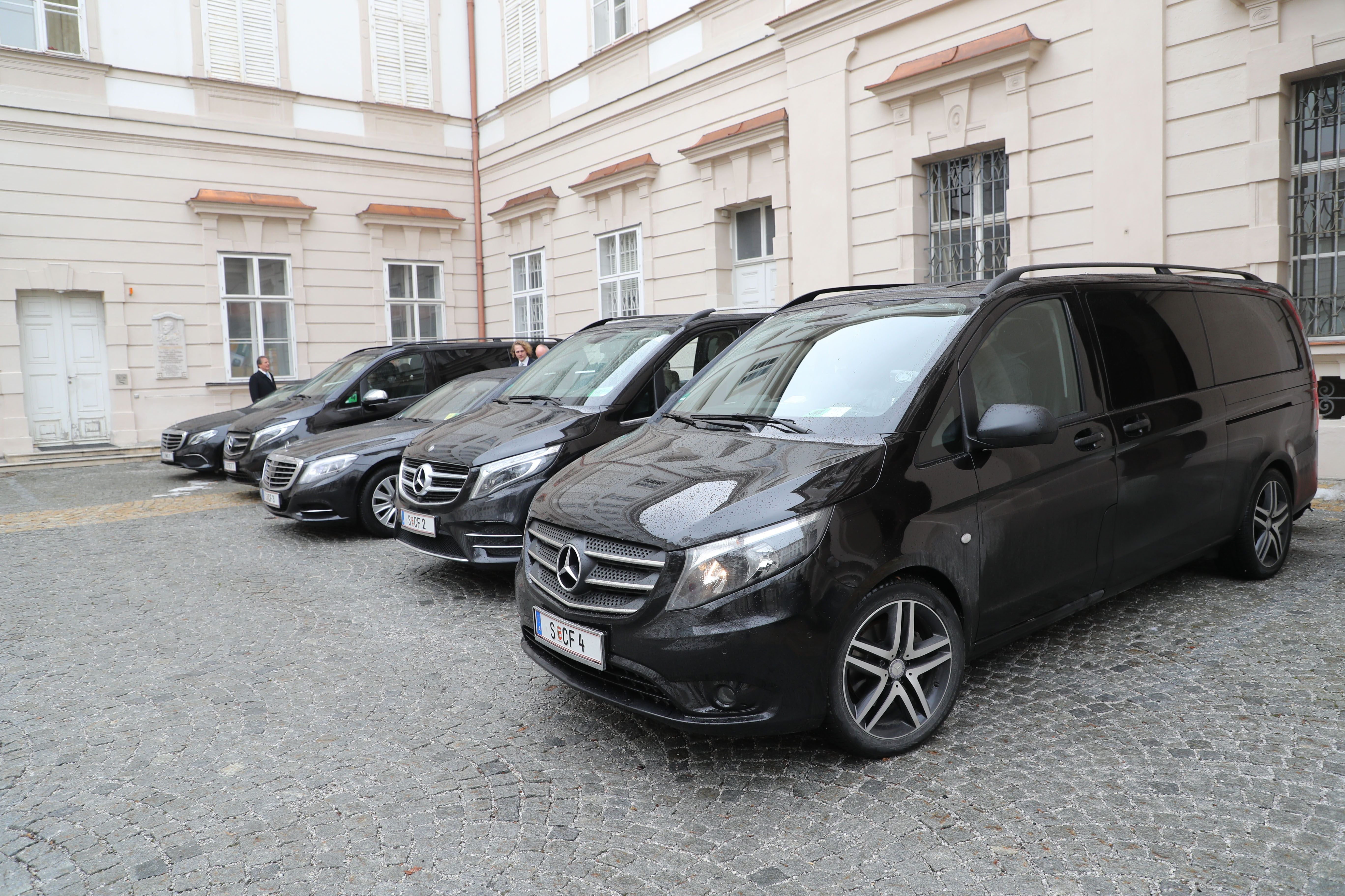 Mehrere schwarze Mercedes-Vans stehen vor einem historischen Gebäude in Salzburg.