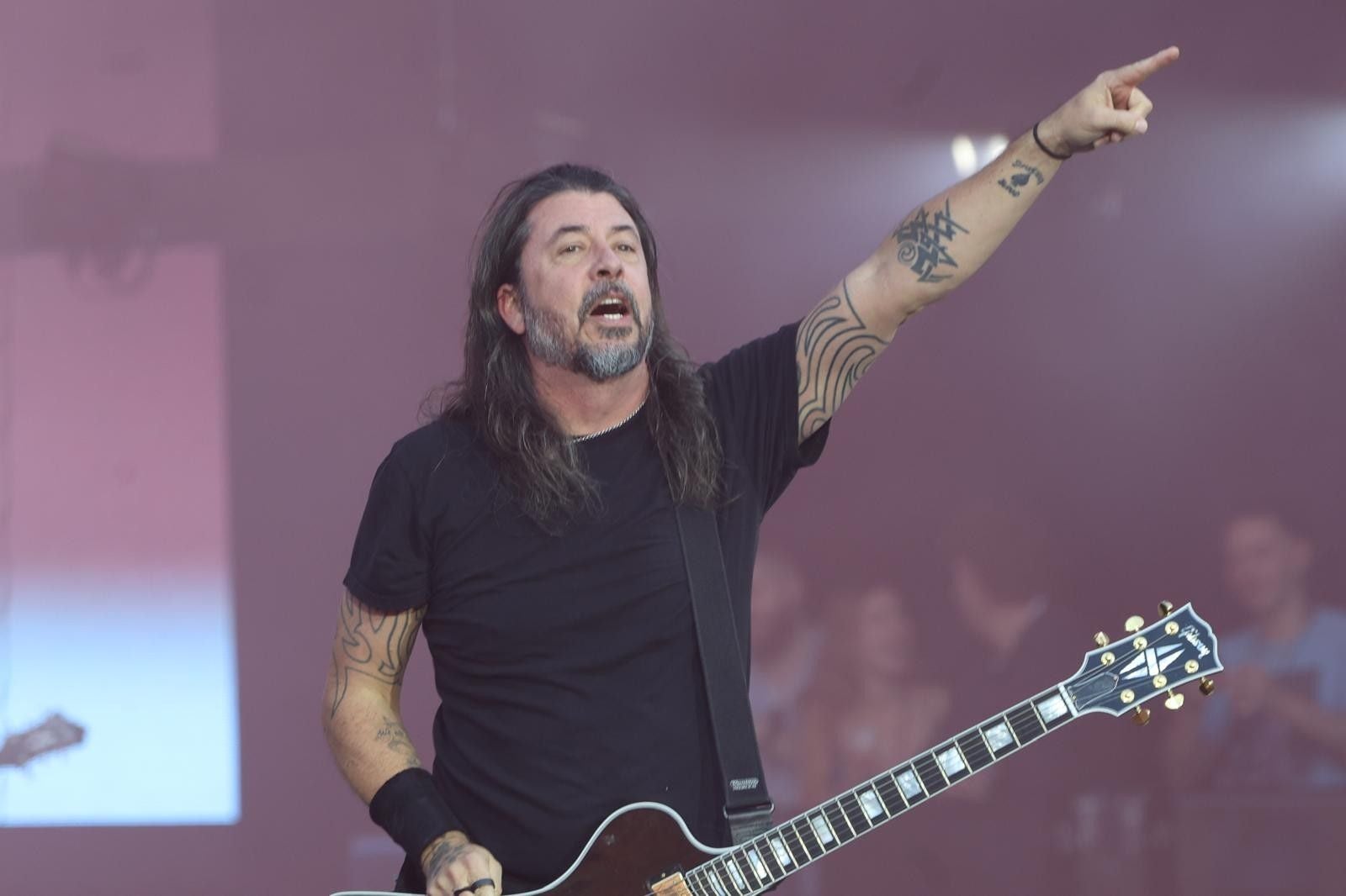 Ein Gitarrist der Foo Fighters spielt auf der Bühne und zeigt mit dem Finger nach oben.