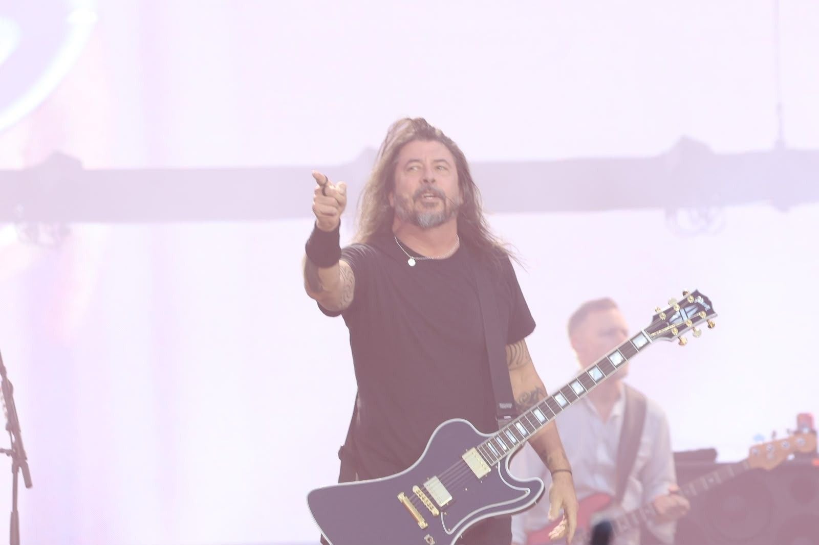 Gitarrist der Foo Fighters spielt auf der Bühne und zeigt mit dem Finger nach vorne.