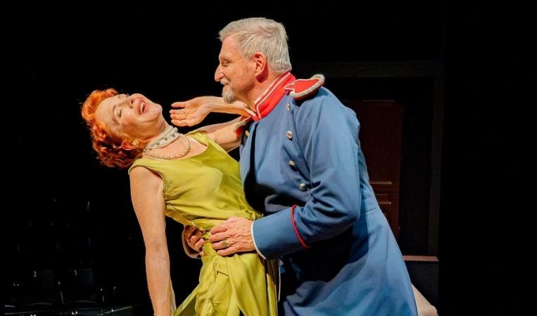 Zwei Schauspieler spielen eine dramatische Szene auf einer Theaterbühne.