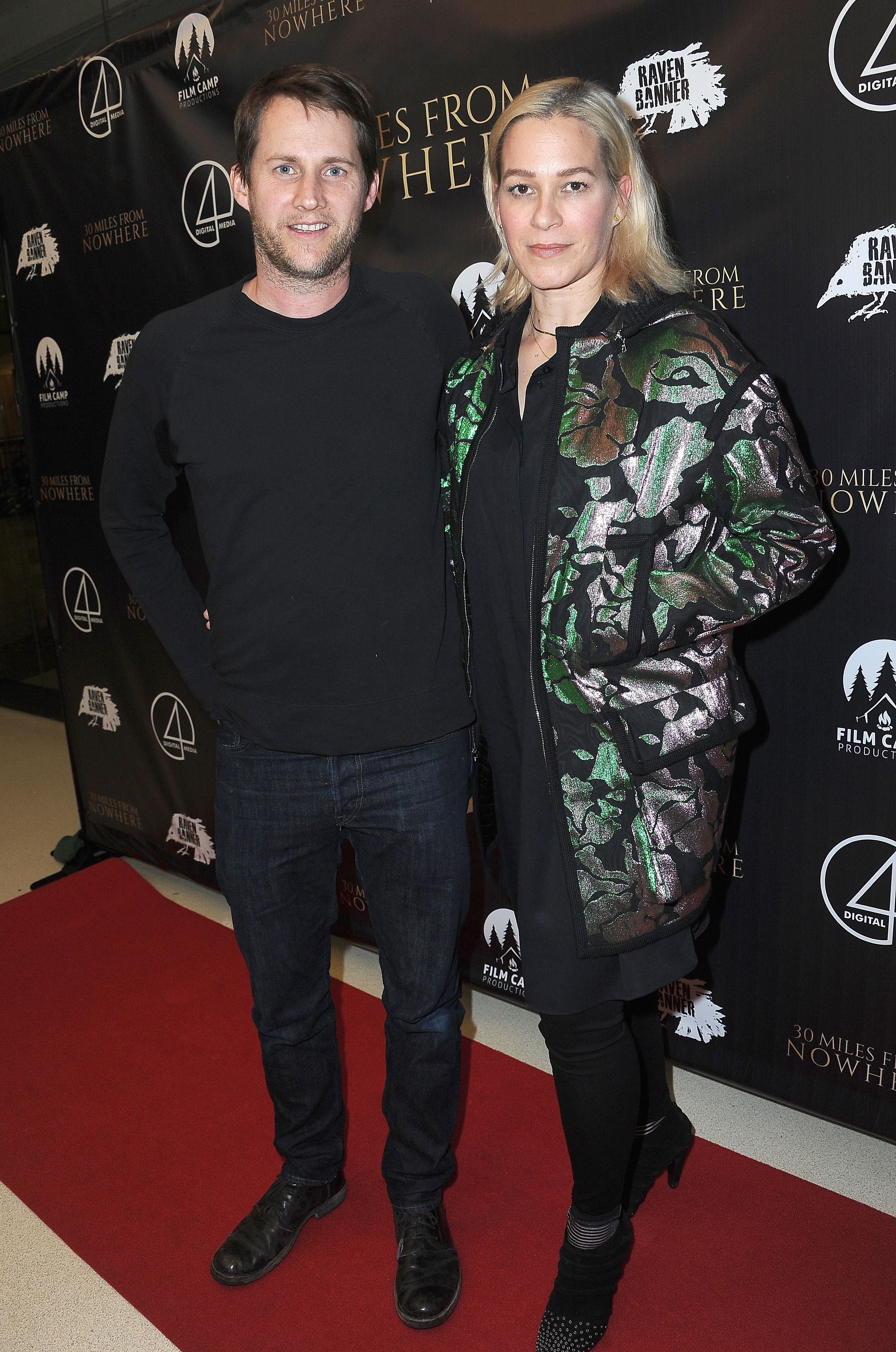 Ein Mann und eine Frau posieren gemeinsam auf einem roten Teppich vor einem Filmpremieren-Backdrop.